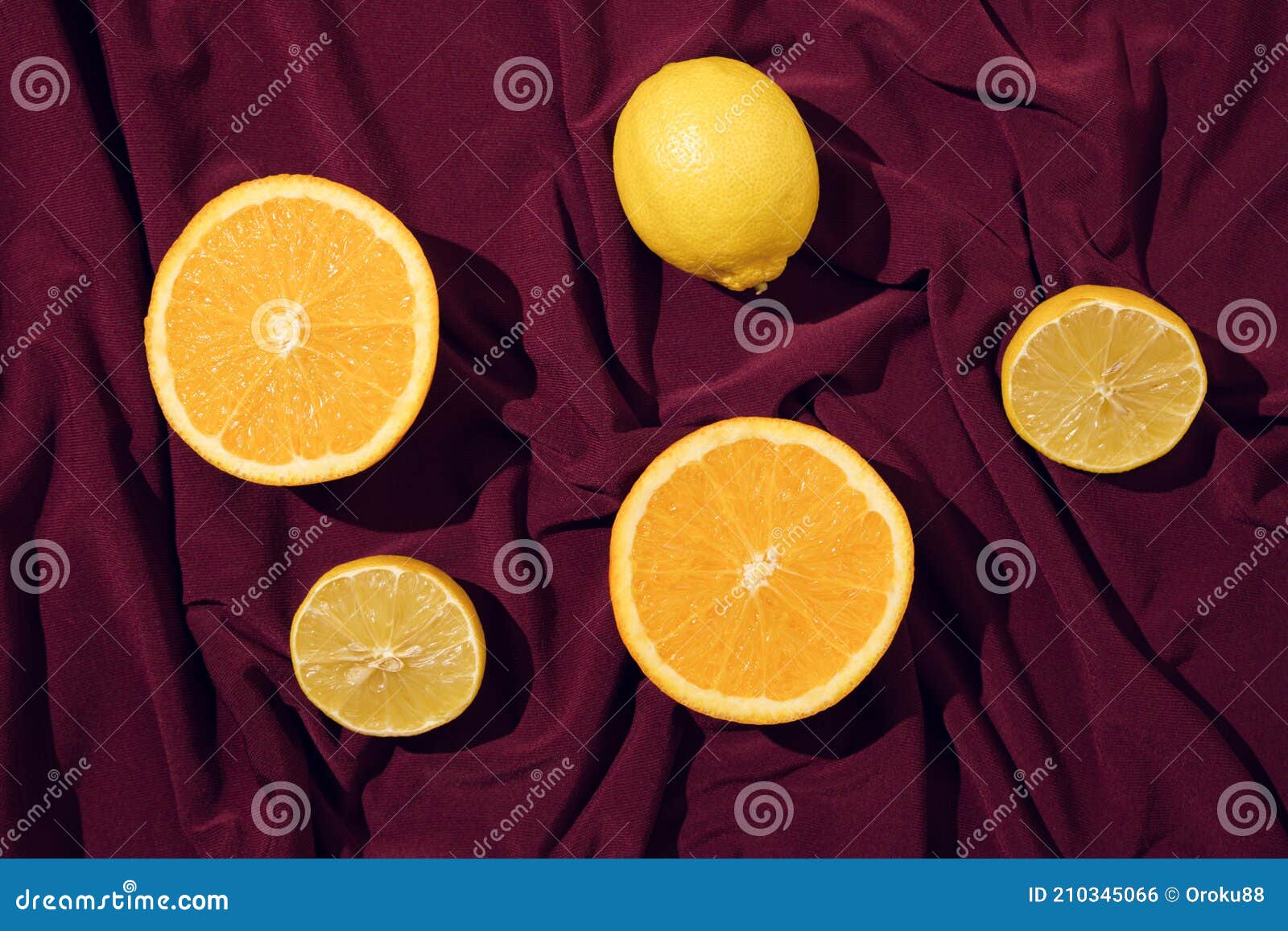 minimal concept of orange slice and lemon on a beautiful dark red silk or saten background. summer fresh fruit idea.