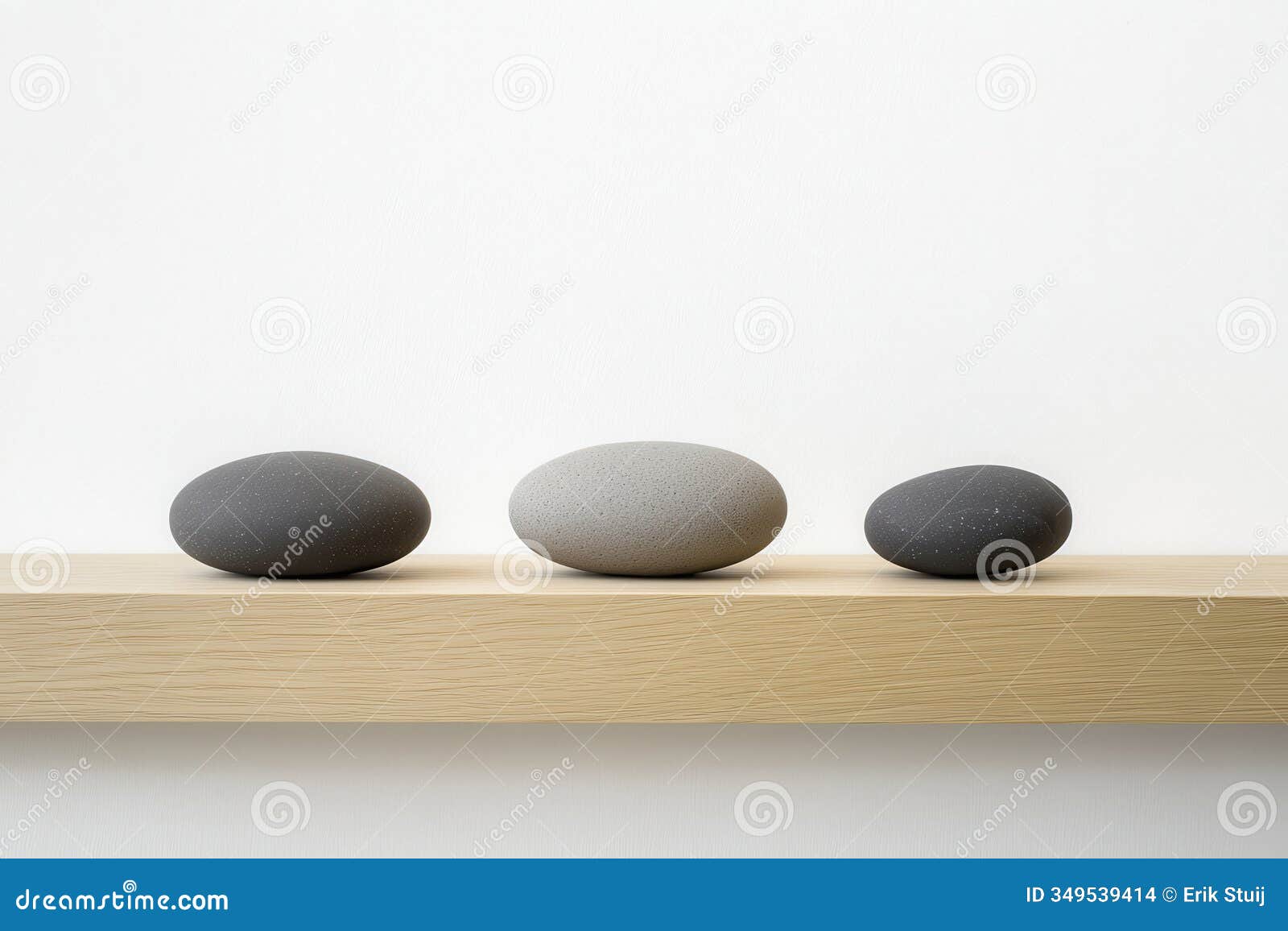 minimalist, photography, a balanced composition of three smooth stones on a light wooden surface