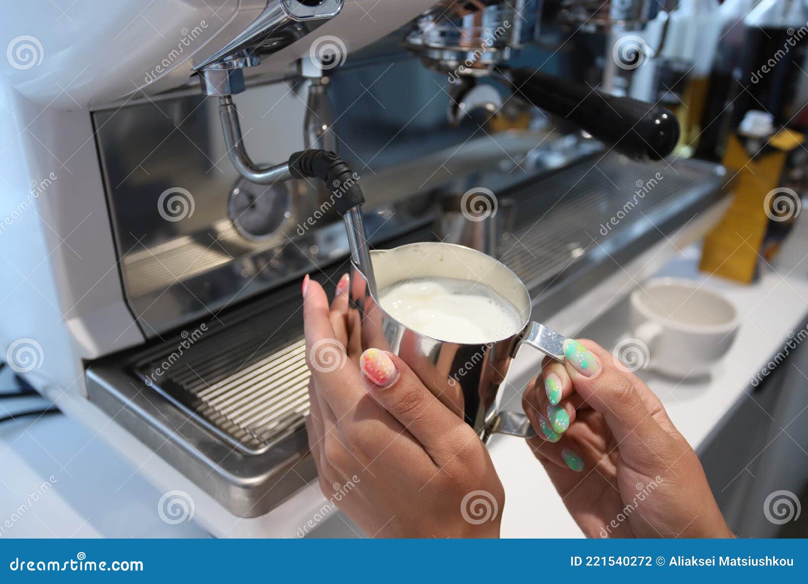 minsk. belarus - 06.06.2021: barista woman in an iron mug froths milk for coffee.