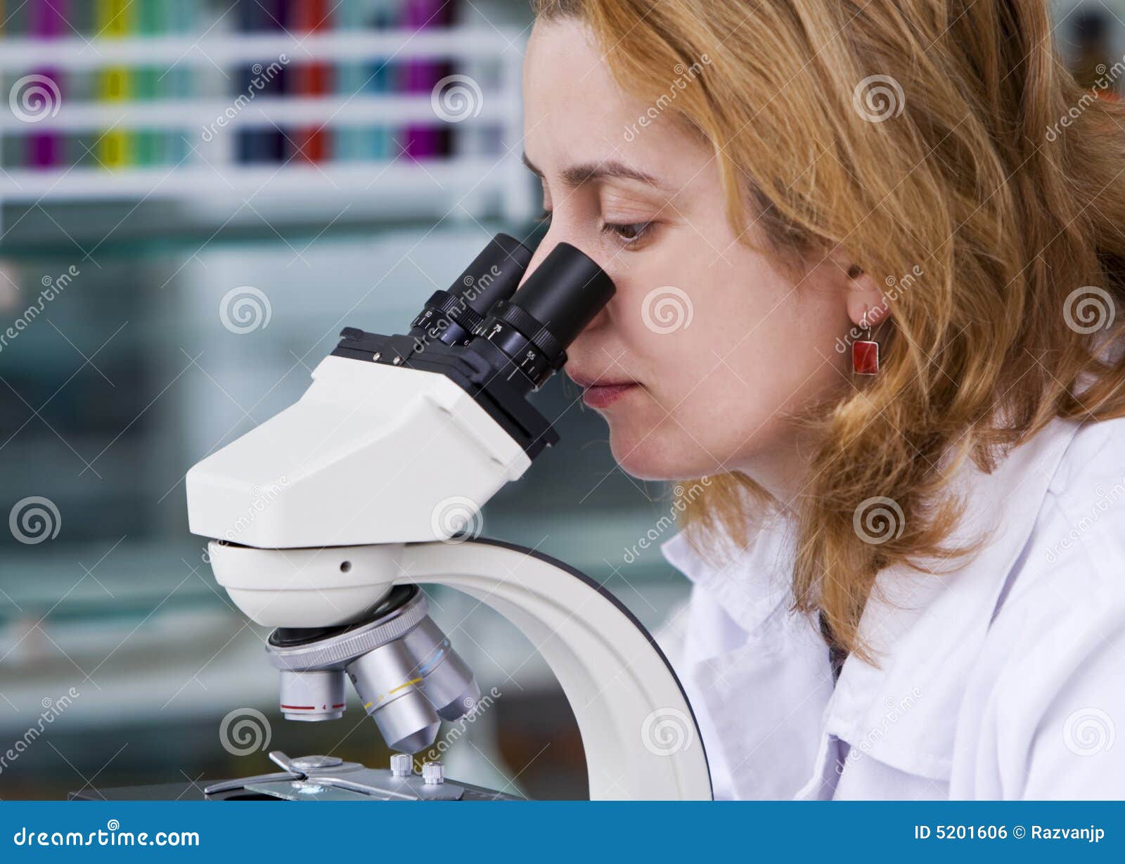 Mirada a través de un microscopio. Investigador de sexo femenino que mira a través de un microscopio en un laboratorio. Se tira con Canon 70-200m m f/2.8L el USM