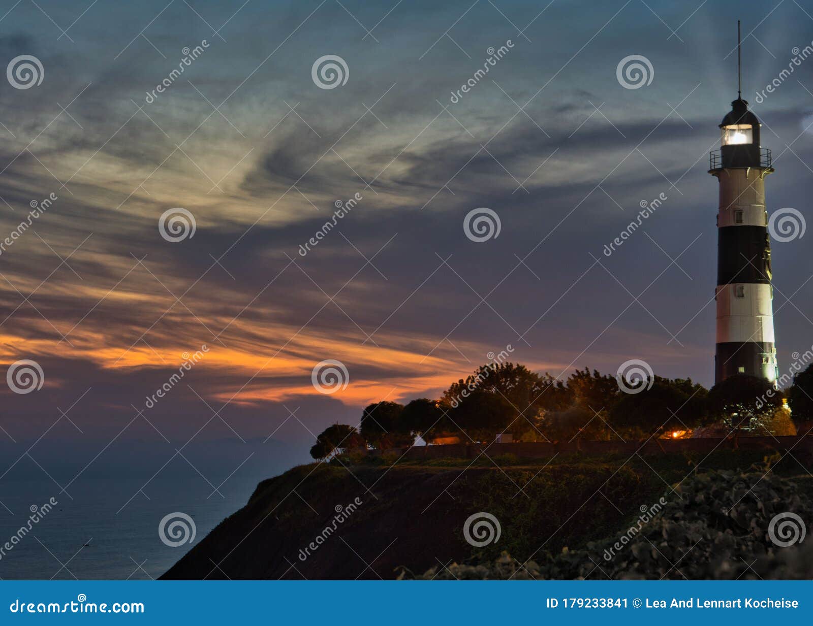 miraflores` famous historical lighthouse on the pacific coast of lima in orange / golden sunset light