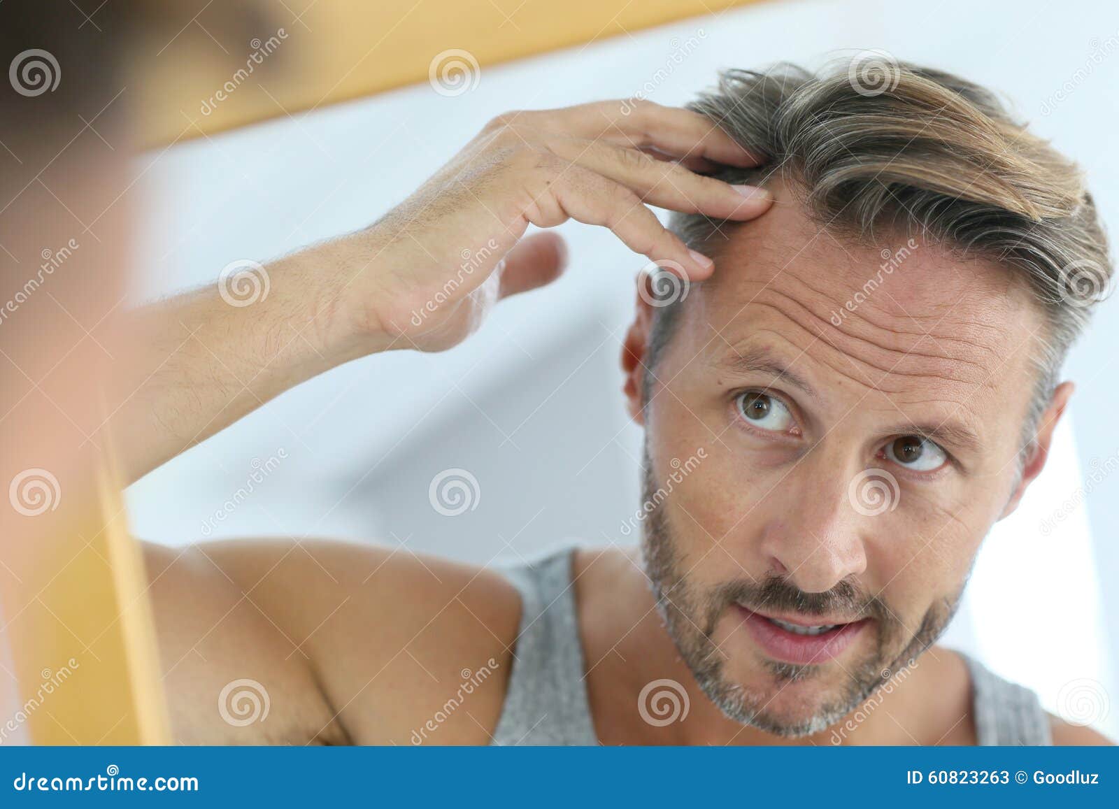 mirror portrait of man concerned by hair loss