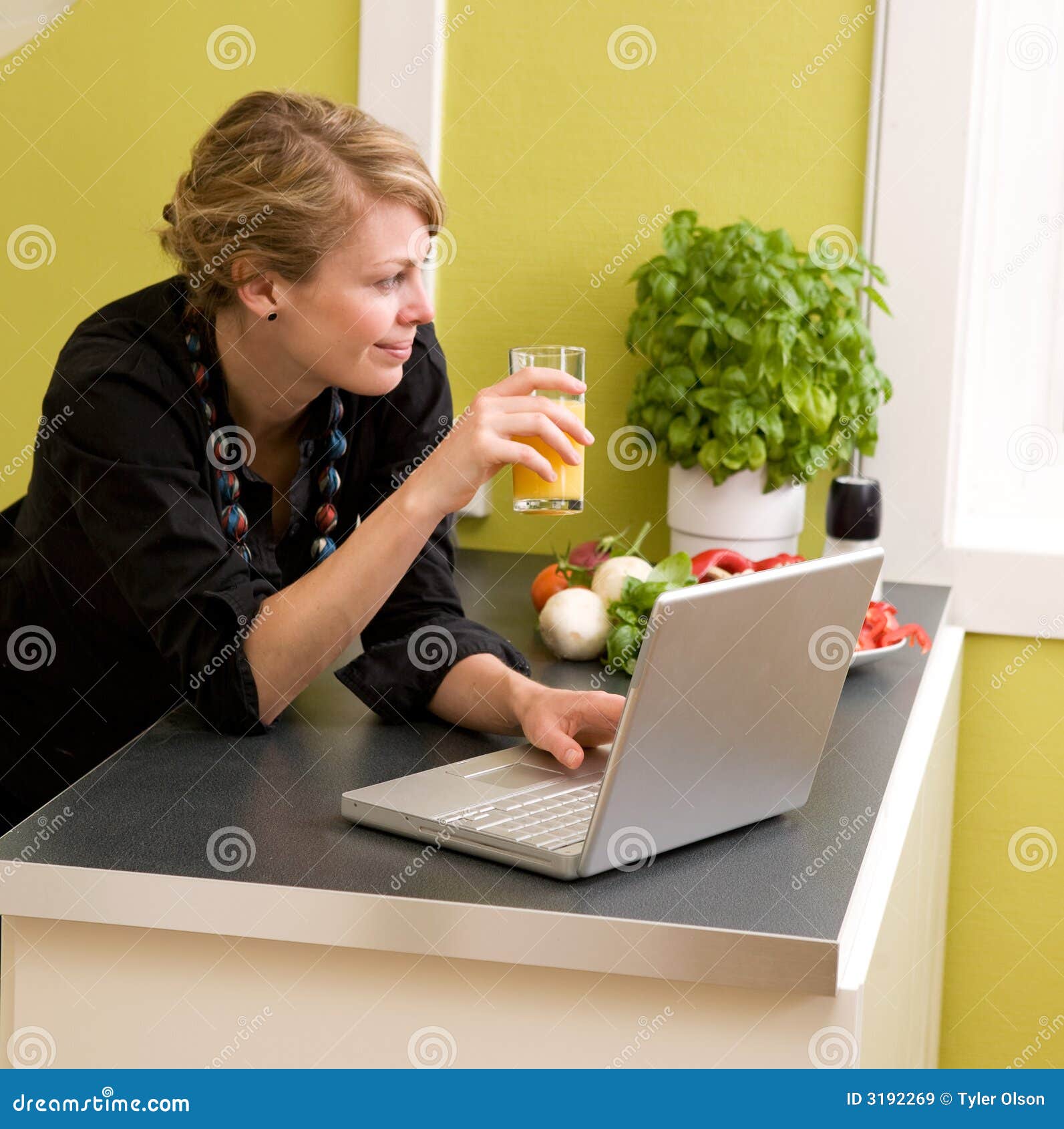 Mittagessen mit Laptop. Ein weibliches Essenmittagessen bei den Laptop im kicthen zu Hause verwenden.