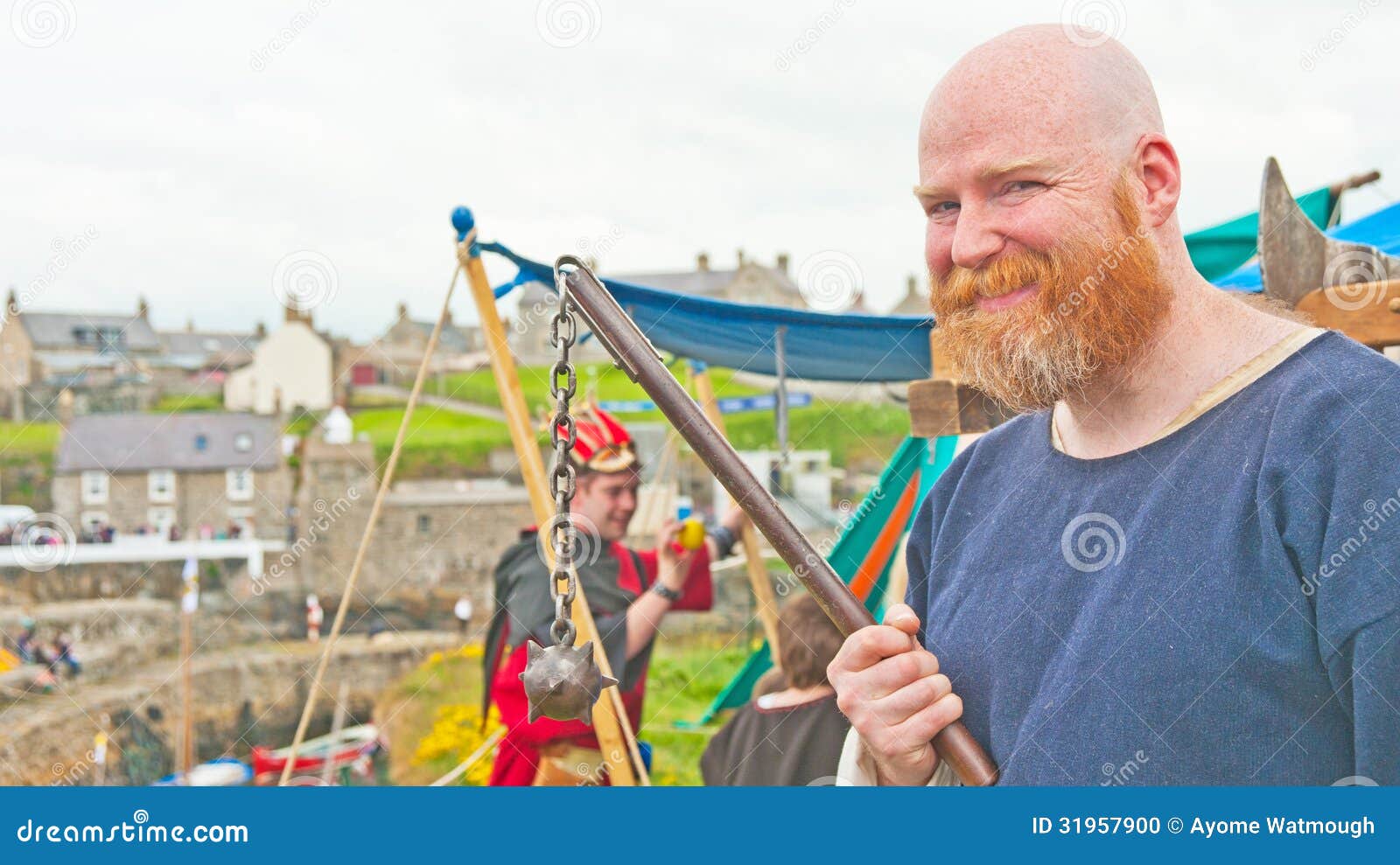 Mittelalterlicher Soldat mit Dreschflegel. Der mittelalterliche Soldat, der gefährliche Waffe hält, nannte einen Dreschflegel am traditionellen schottischen Boots-Festival, das an Portsoy auf 16. und am 17. Juni 2013 gehalten wurde.