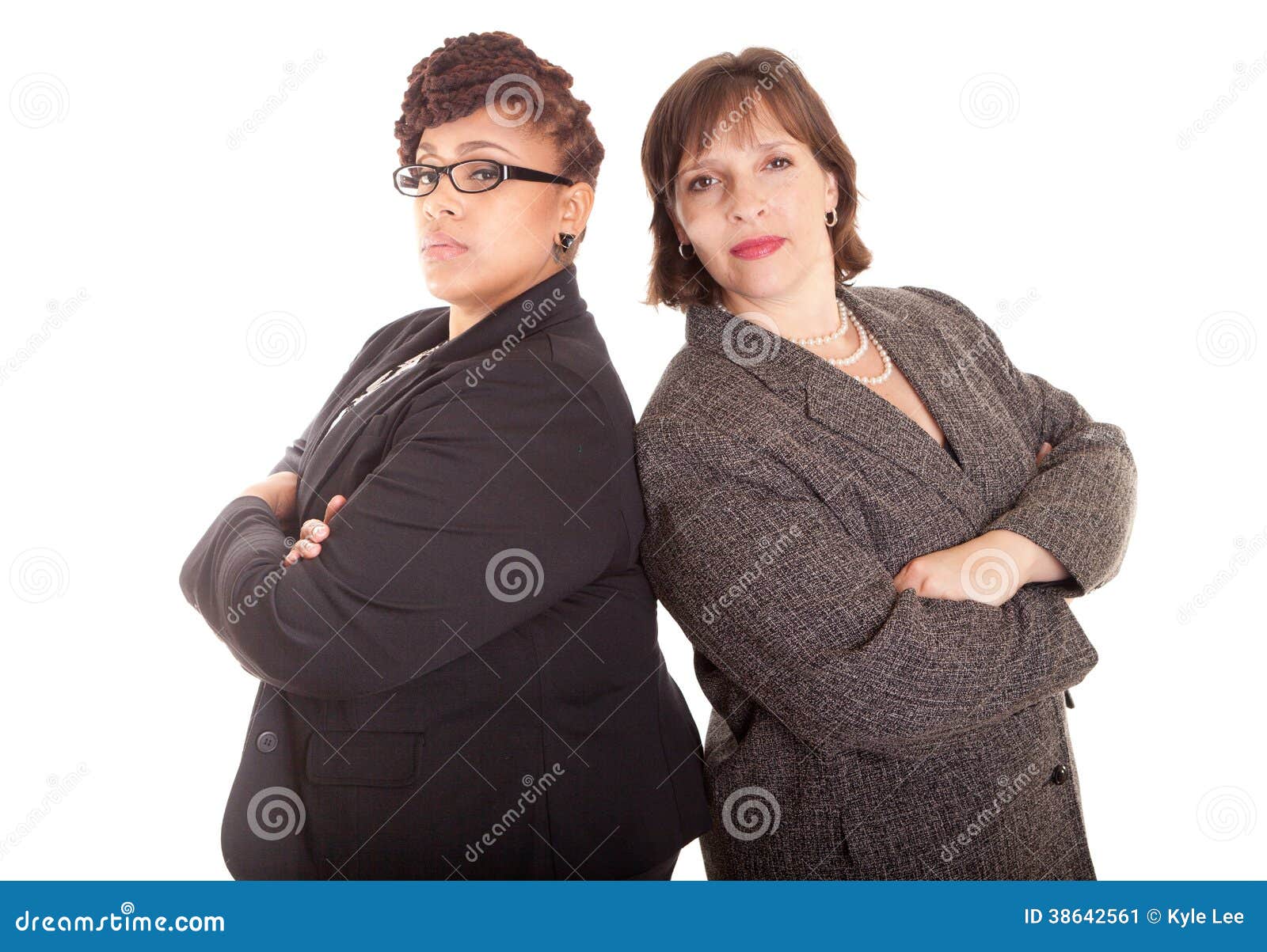 Two confident plus size mixed race business women on a white background standing back to back in a confident sly pose