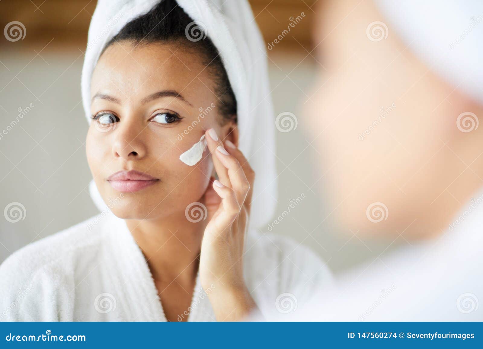 mixed race woman applying face cream