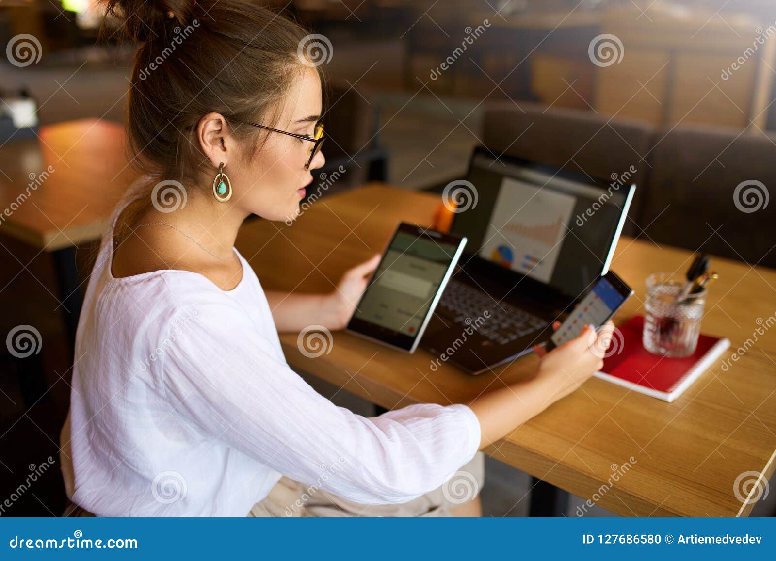 mixed race woman in glasses working with multiple electronic internet devices. freelancer businesswoman has tablet and