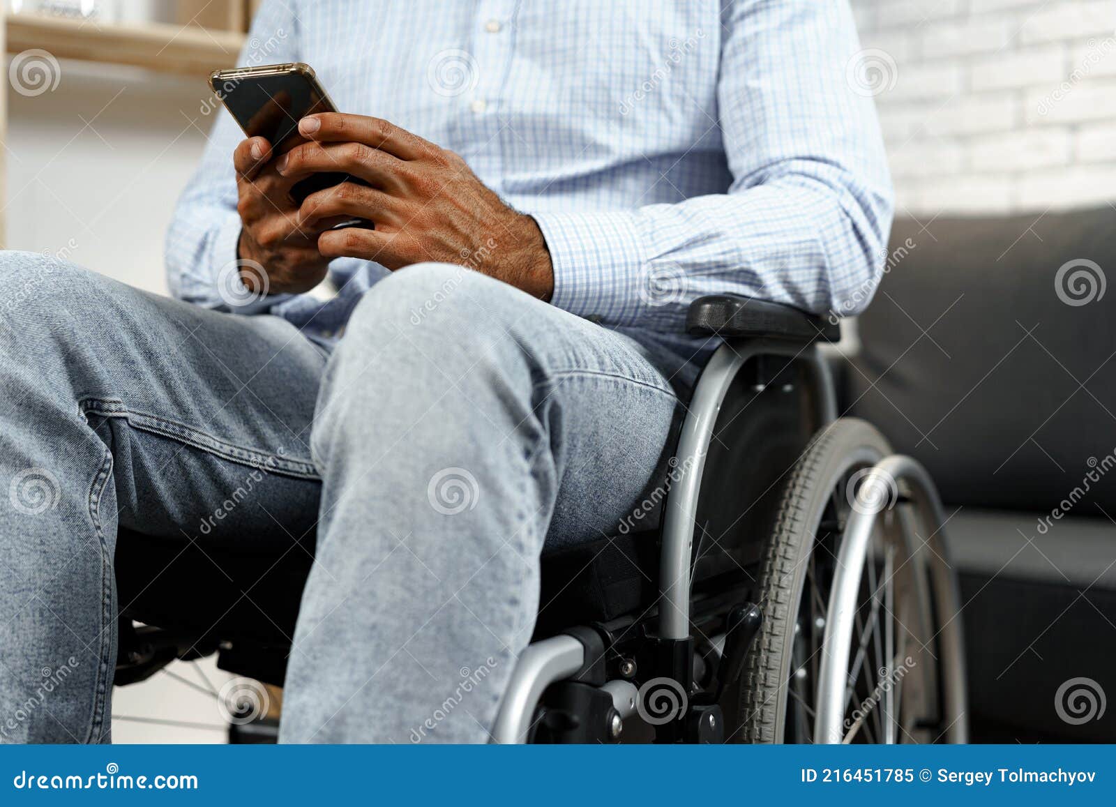 Mixed Raced Disabled Man Sitting in a Wheelchair and Using Smartphone