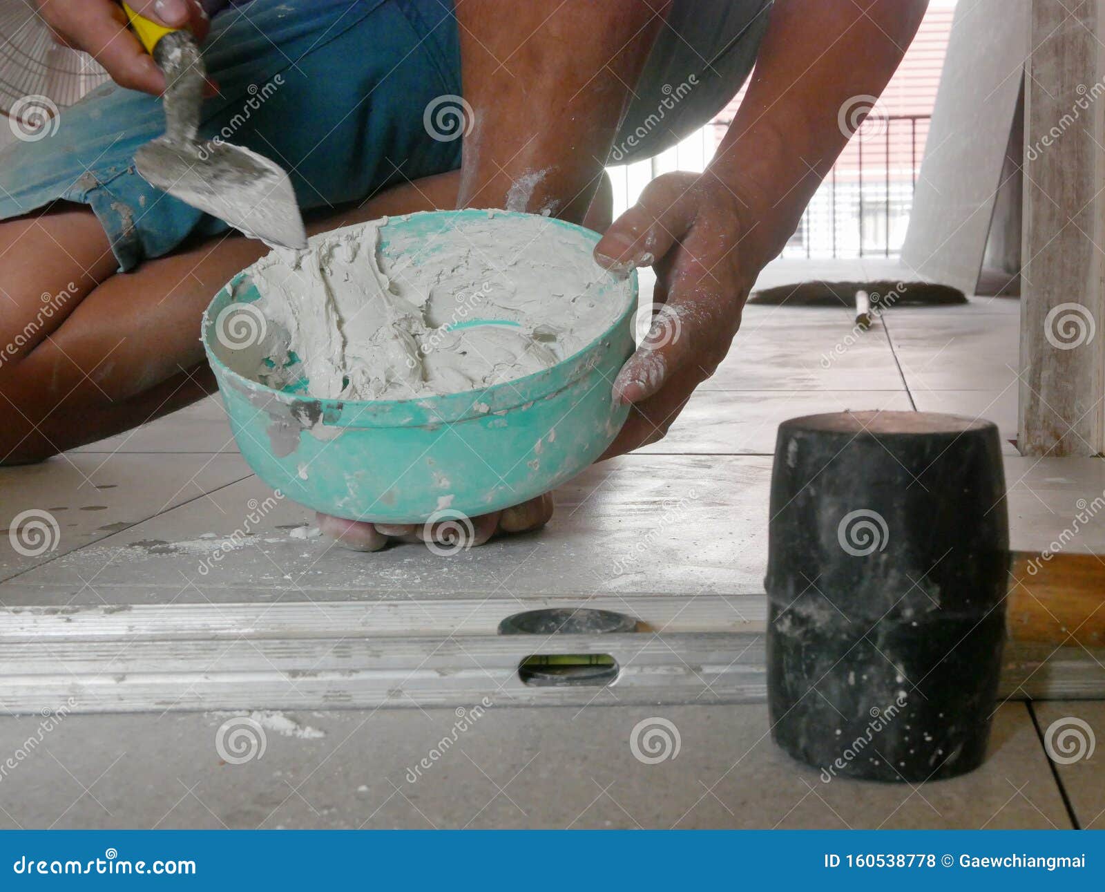 Mixed Tile Grout in a Plastic Bowl in a Construction Worker`s Hands