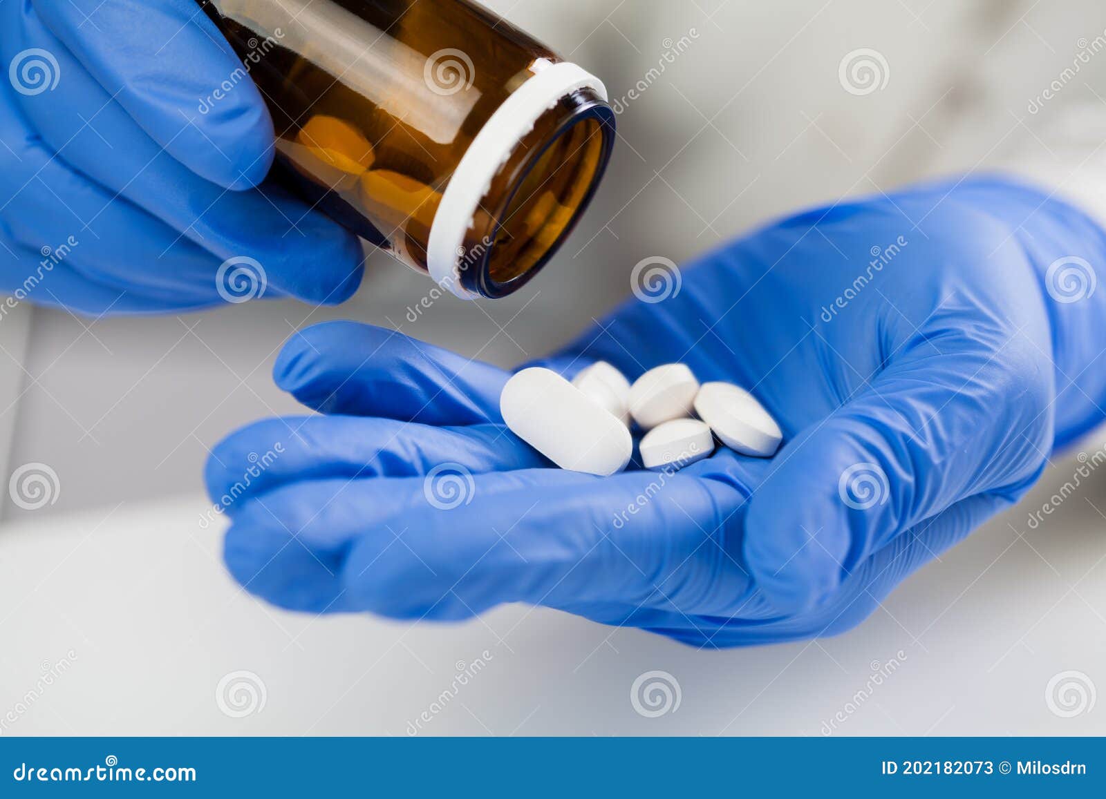 medical practitioner wearing blue surgical latex gloves holding medicine bottle