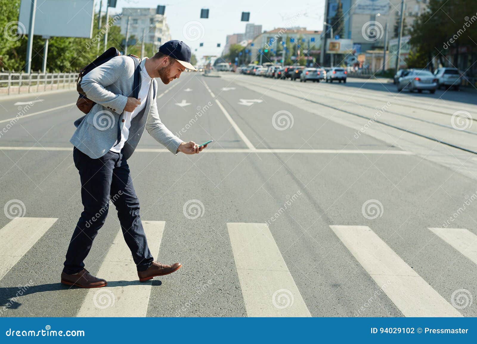 Man on mobile phone cross the road at a pedestrian crossing. Ho