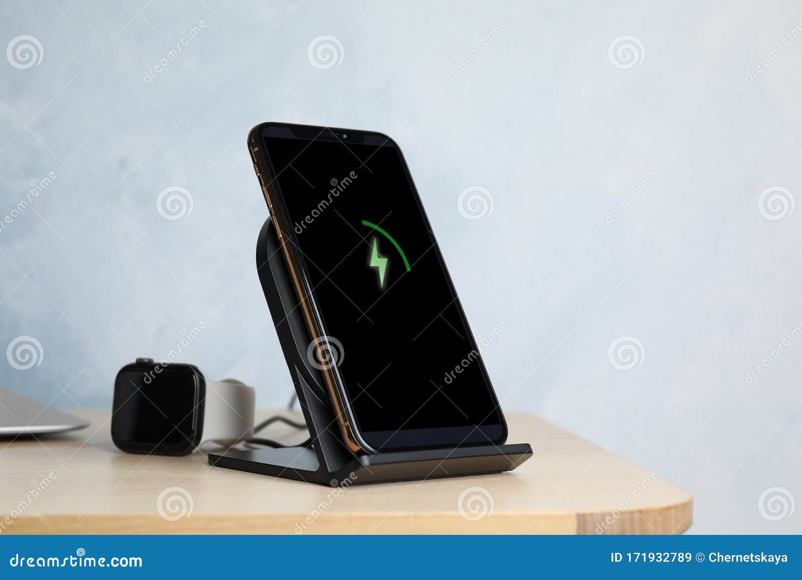 Mobile Phone Charging with Wireless Pad and Smartwatch on Table Stock