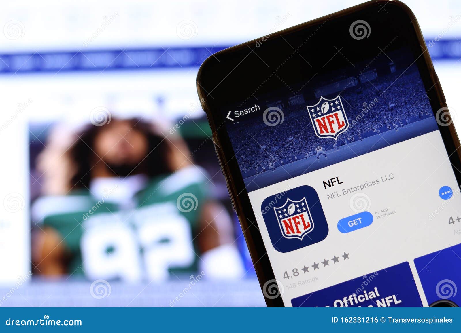 Mobile Phone with NFL Logo on Screen Close Up with Website on Laptop