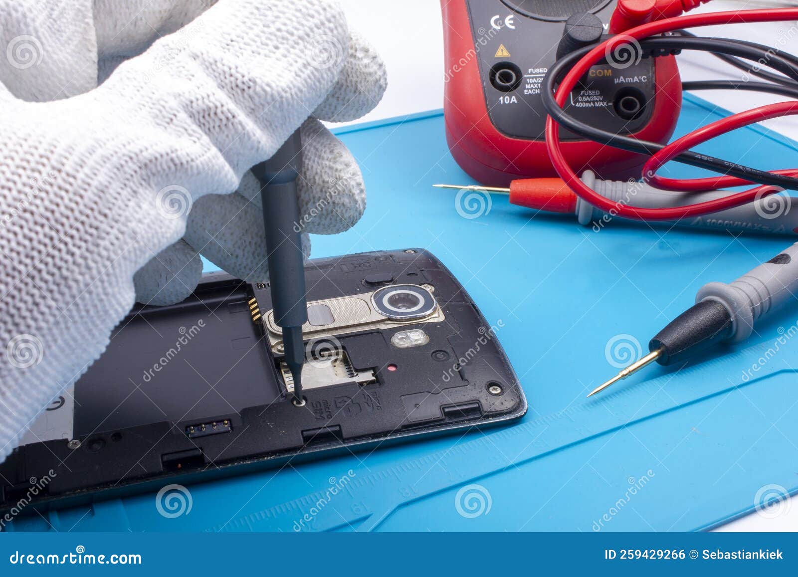 mobile phone repair. the service technician disassembles the phone on the esd mat with a screwdriver