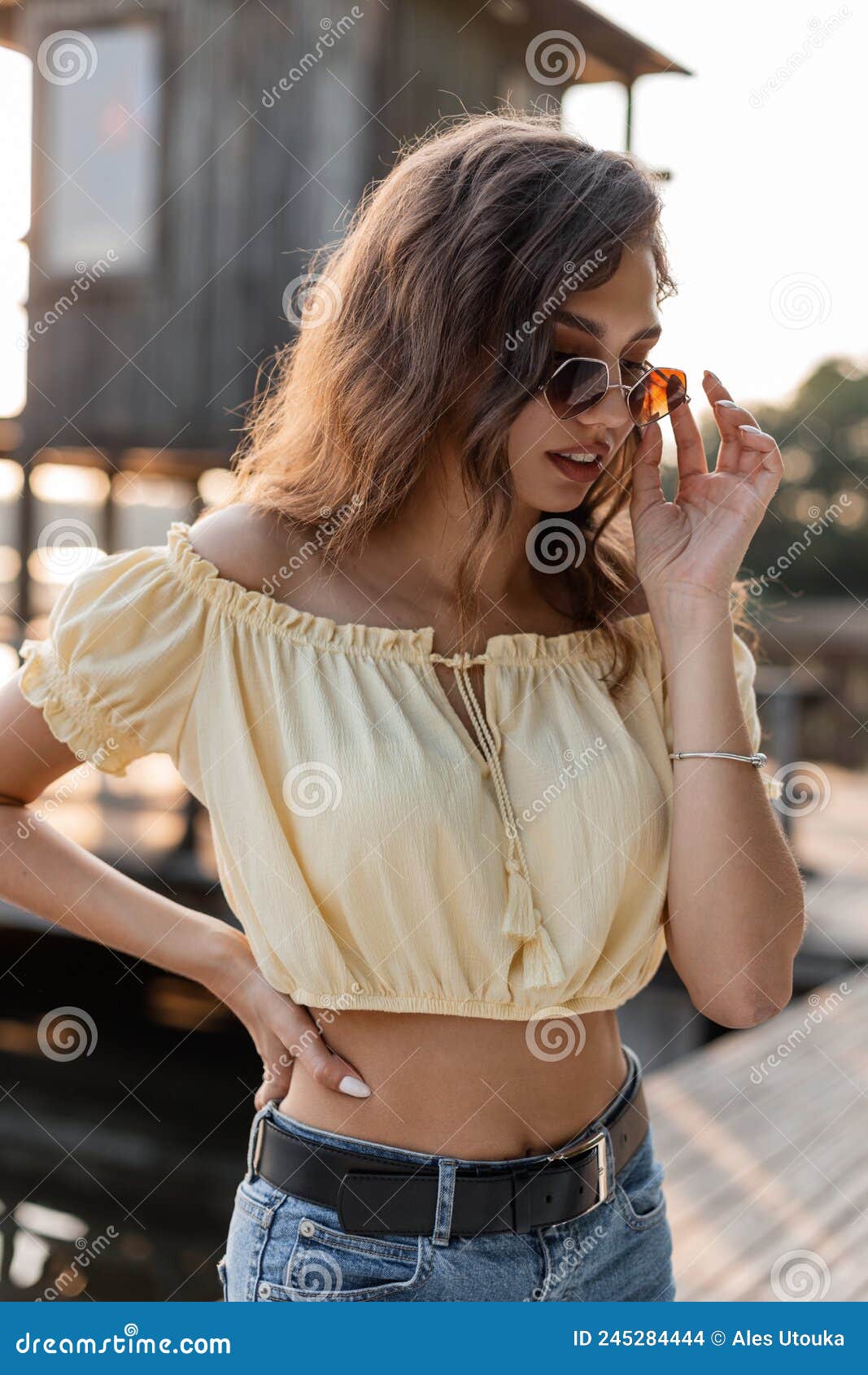 Moda Mujer Joven Hipster En Una Elegante Blusa Amarilla Con Vaqueros Azules  Y Gafas De Sol De Moda En El Muelle Cerca De La Playa Foto de archivo -  Imagen de adulto