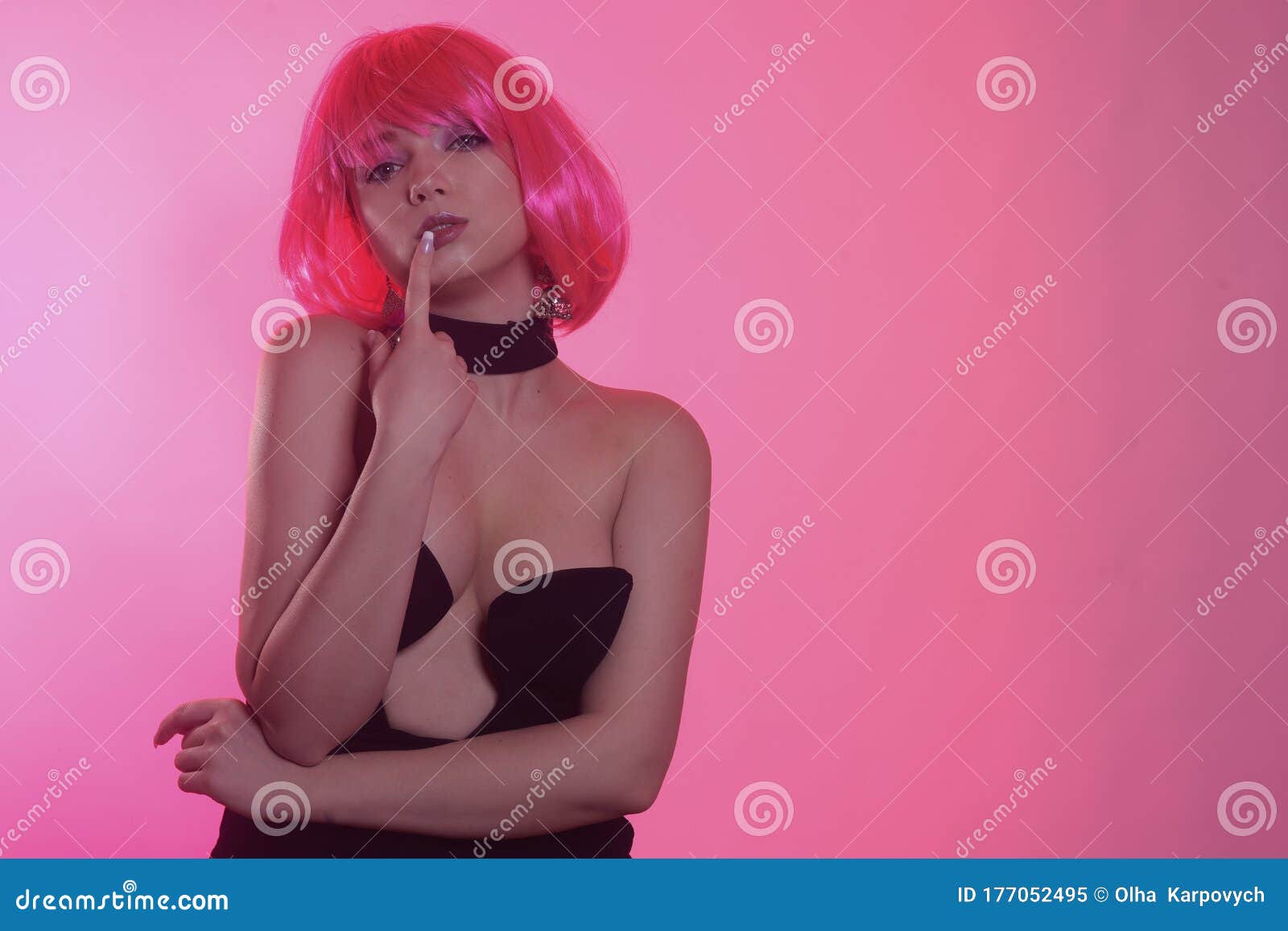 model with pink short hair in a black stylish dress. posh girl posing. very bright image. girl with a quack on a pink background.