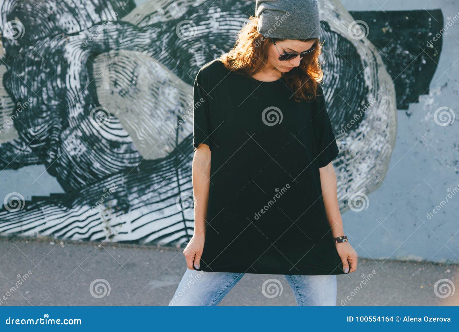 model wearing plain tshirt and sunglasses posing over street wall