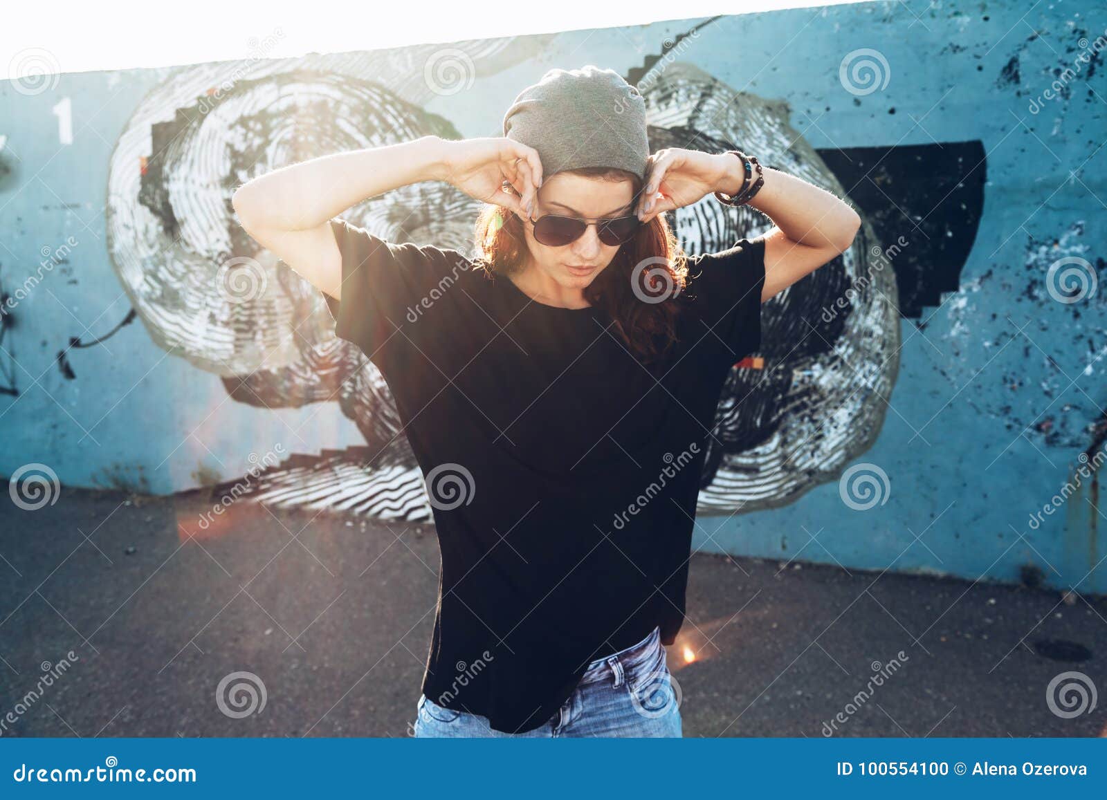 model wearing plain tshirt and sunglasses posing over street wall