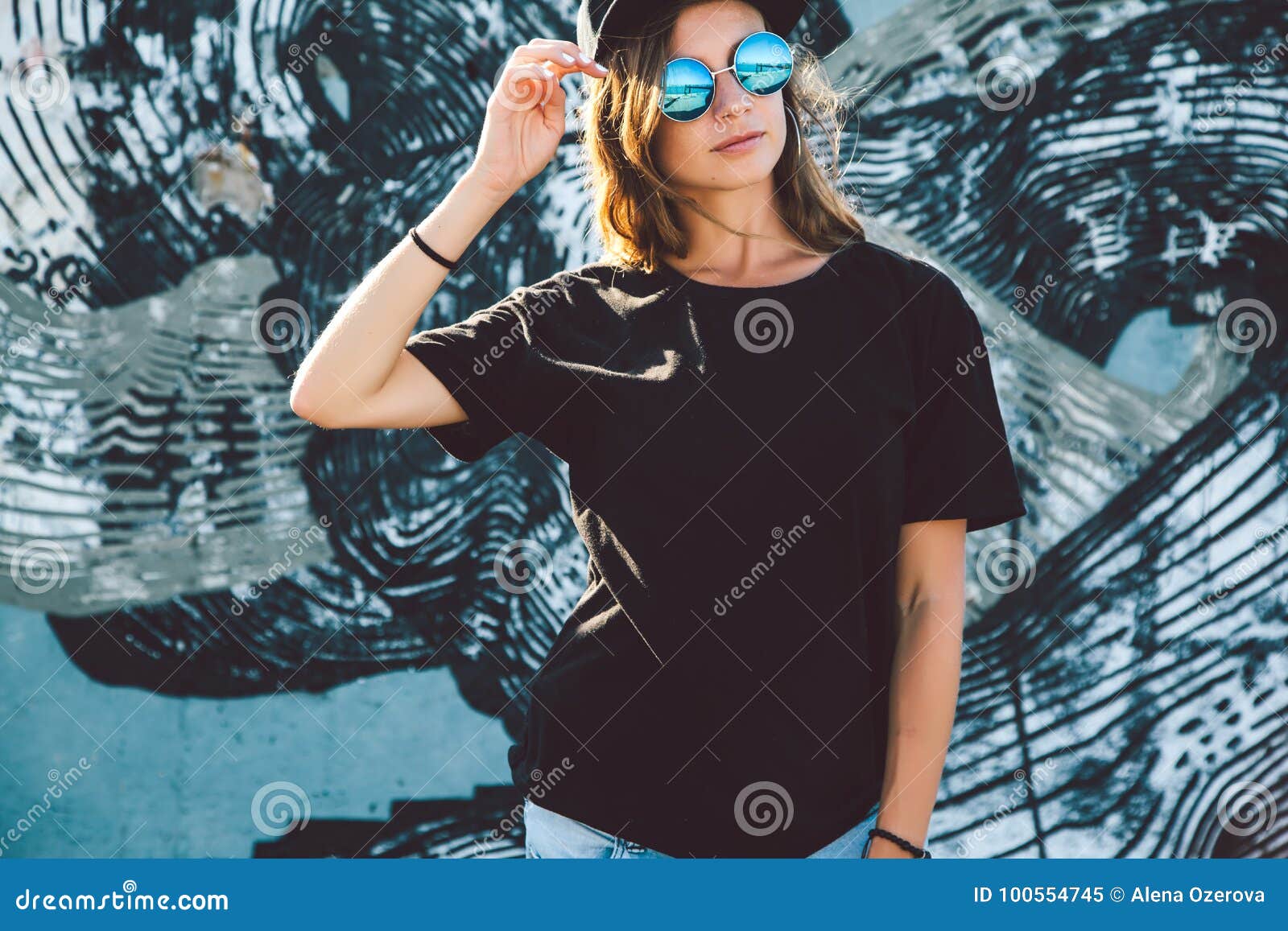 model wearing plain tshirt and sunglasses posing over street wall