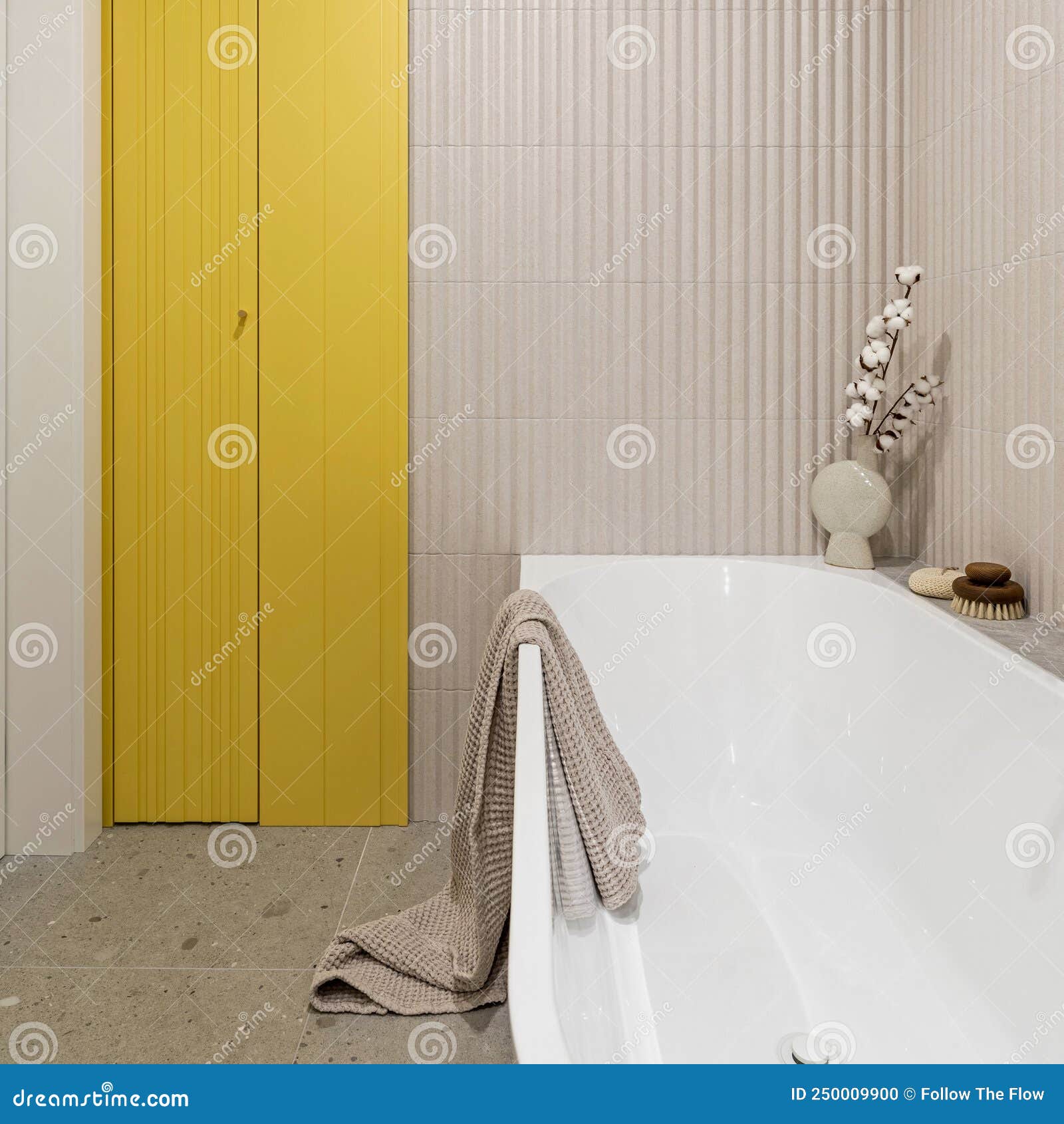 modern bright bathroom with lamella wall. big white bath with brown towel and cotton