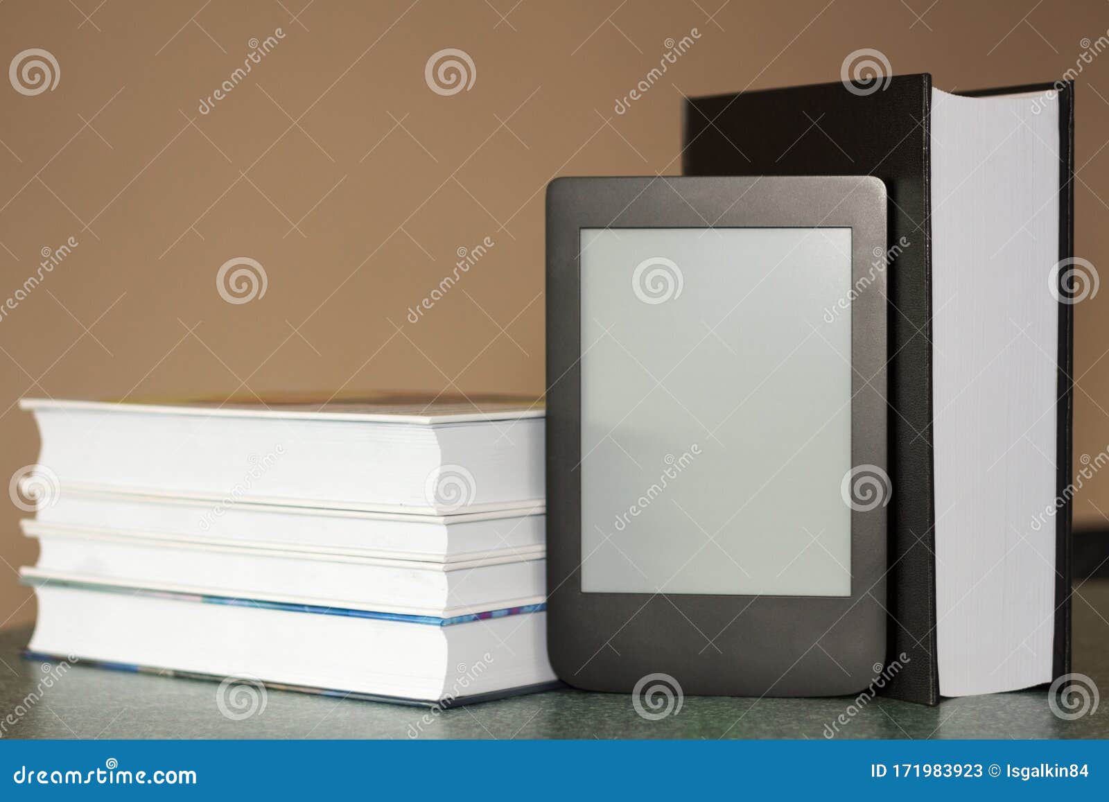 modern e-book on the background of a stack of thick paper books. close-up with selective focus