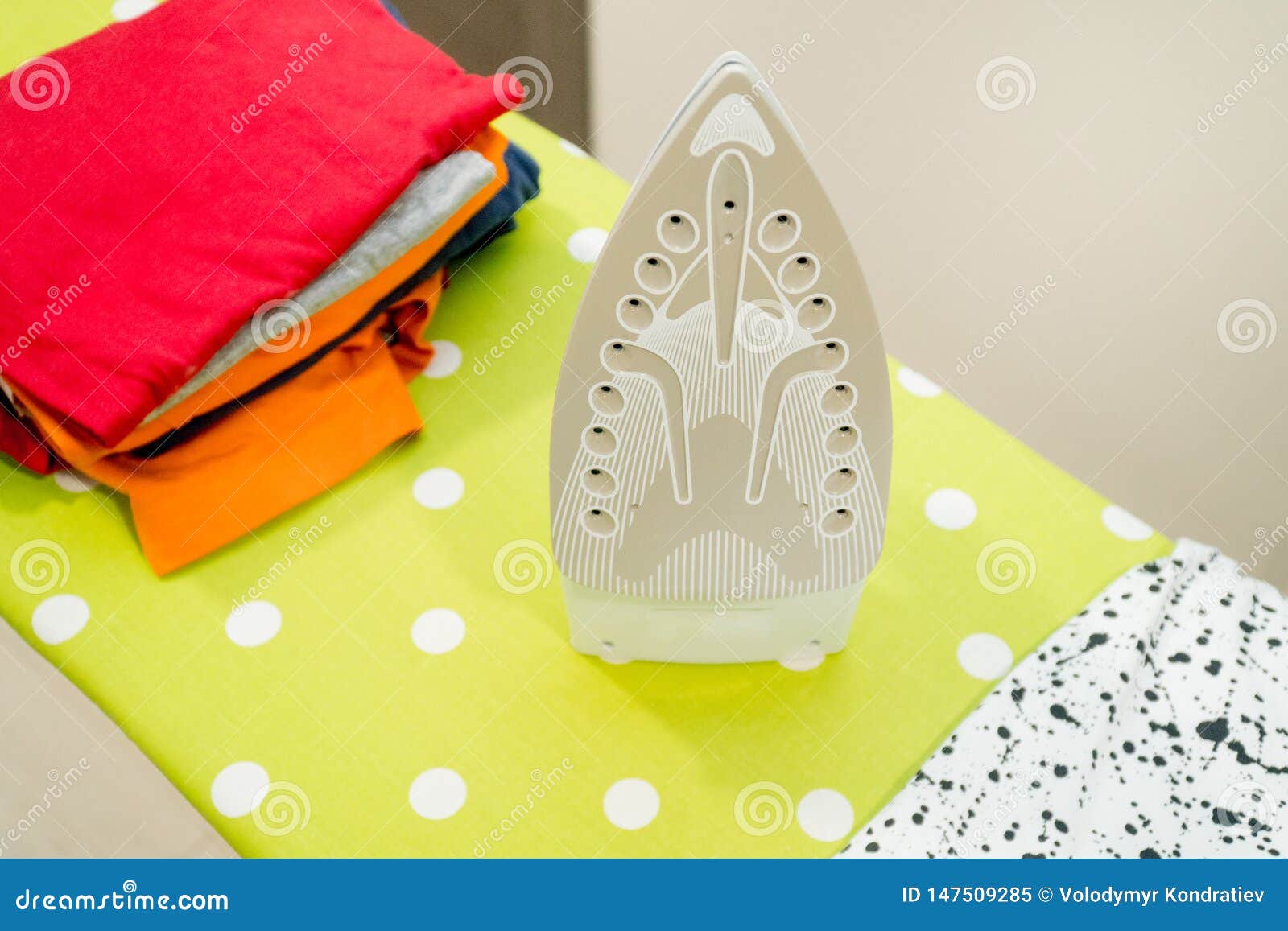 Modern Electric Iron and Pile of Clothes on Ironing Board Stock Image