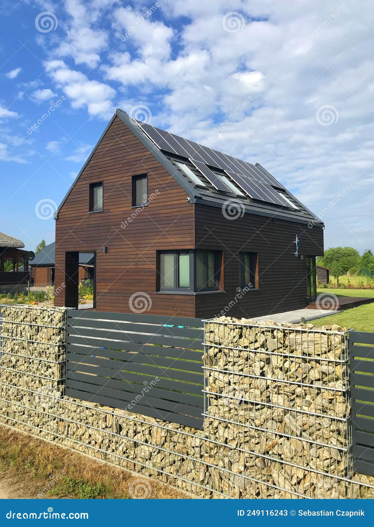 modern energy efficient house with solar panels and gabion fence