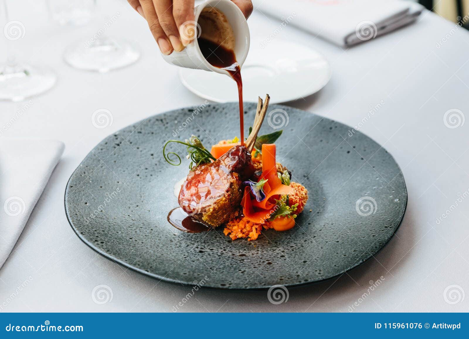 modern french cuisine: roasted lamb neck & rack served with carrot, yellow curry and lamb sauce. served in black stone plate.