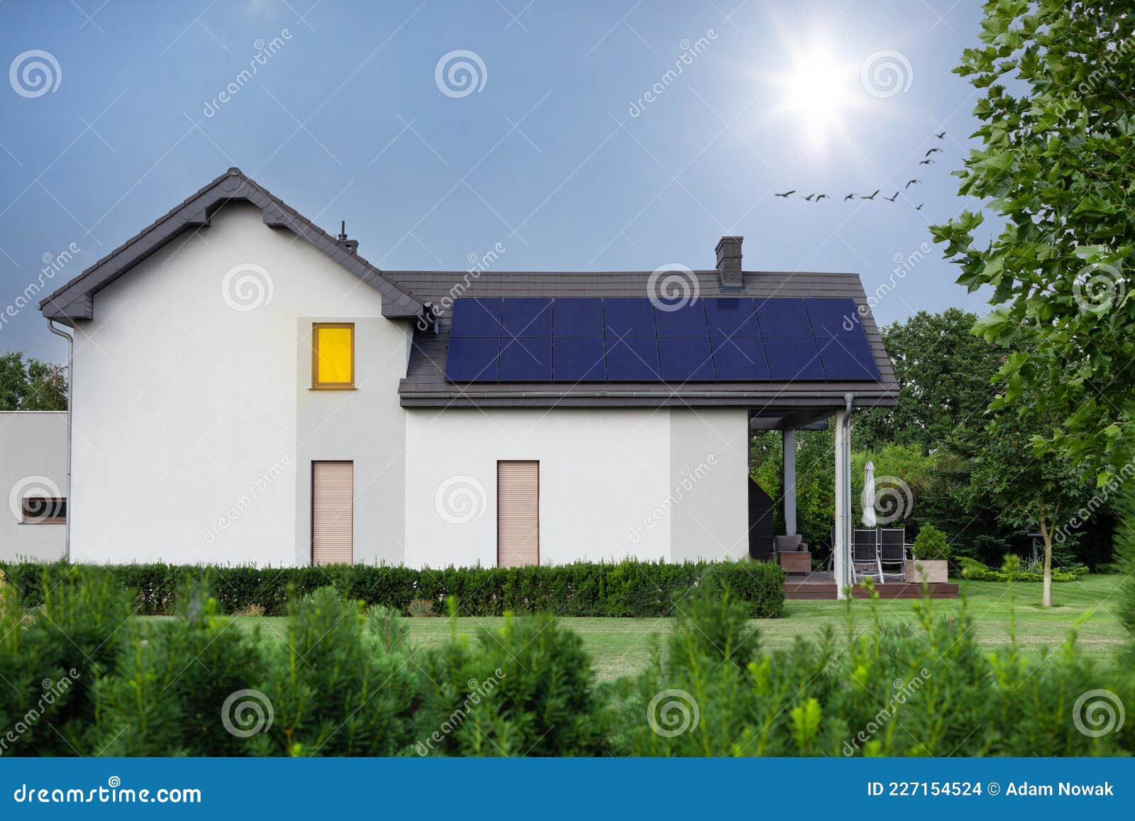 modern house and beautiful garden with solar panels. clear sky, sun