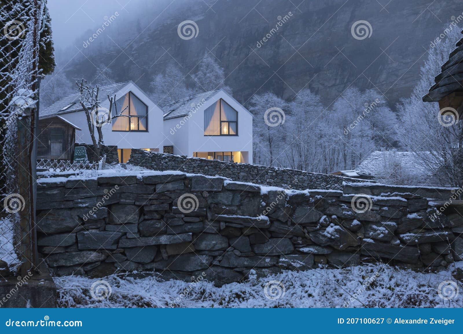 modern with house with large windows surronded by mountain, snow and fog