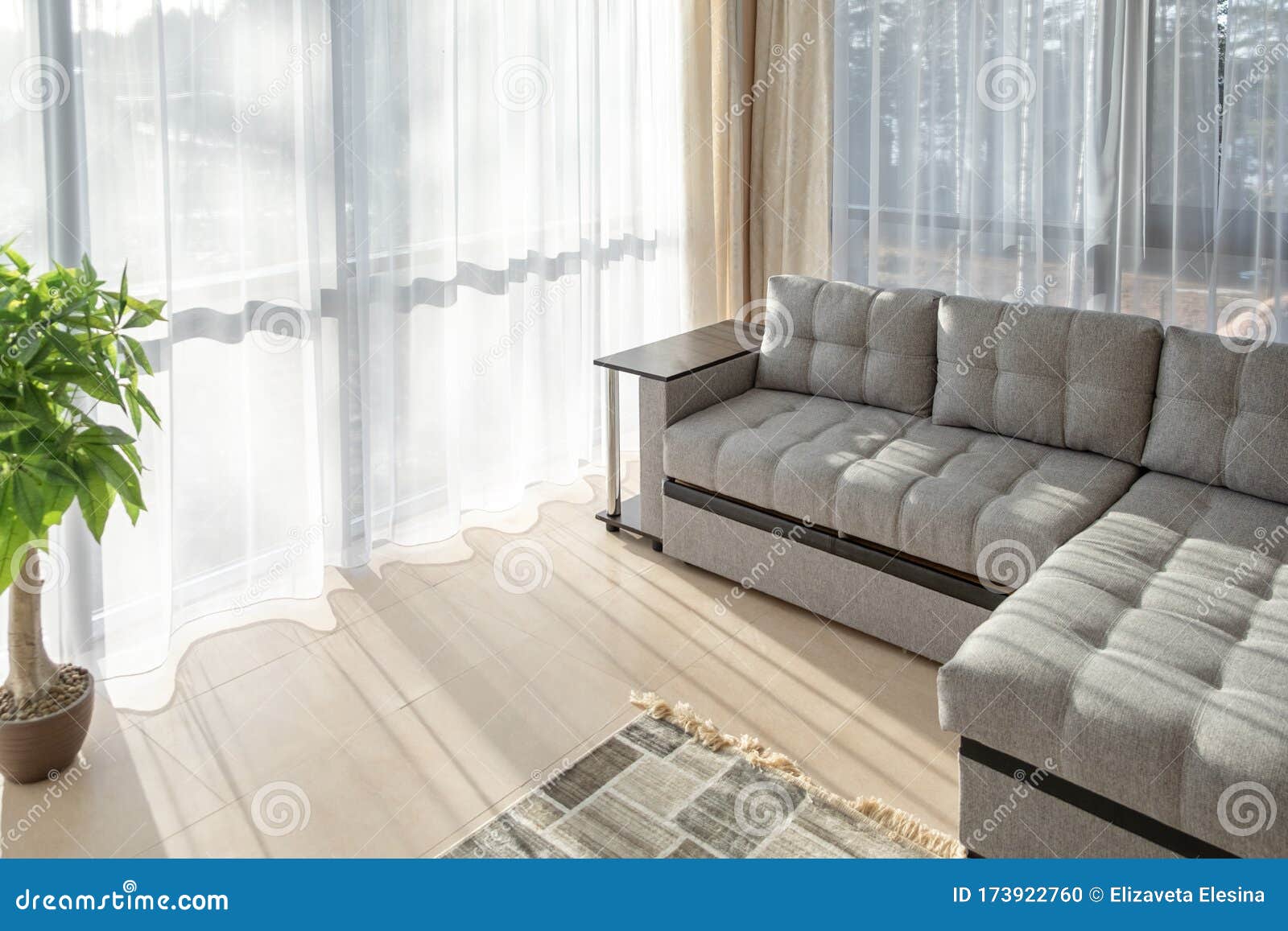 Modern Interior with Big Sofa and a Large Windows. Morning Sunlight