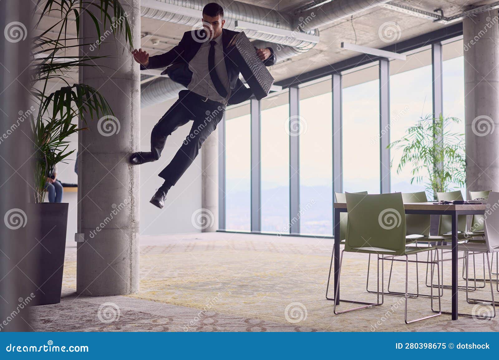in the modern office, a businessman with a briefcase captivates everyone as he performs thrilling aerial acrobatics