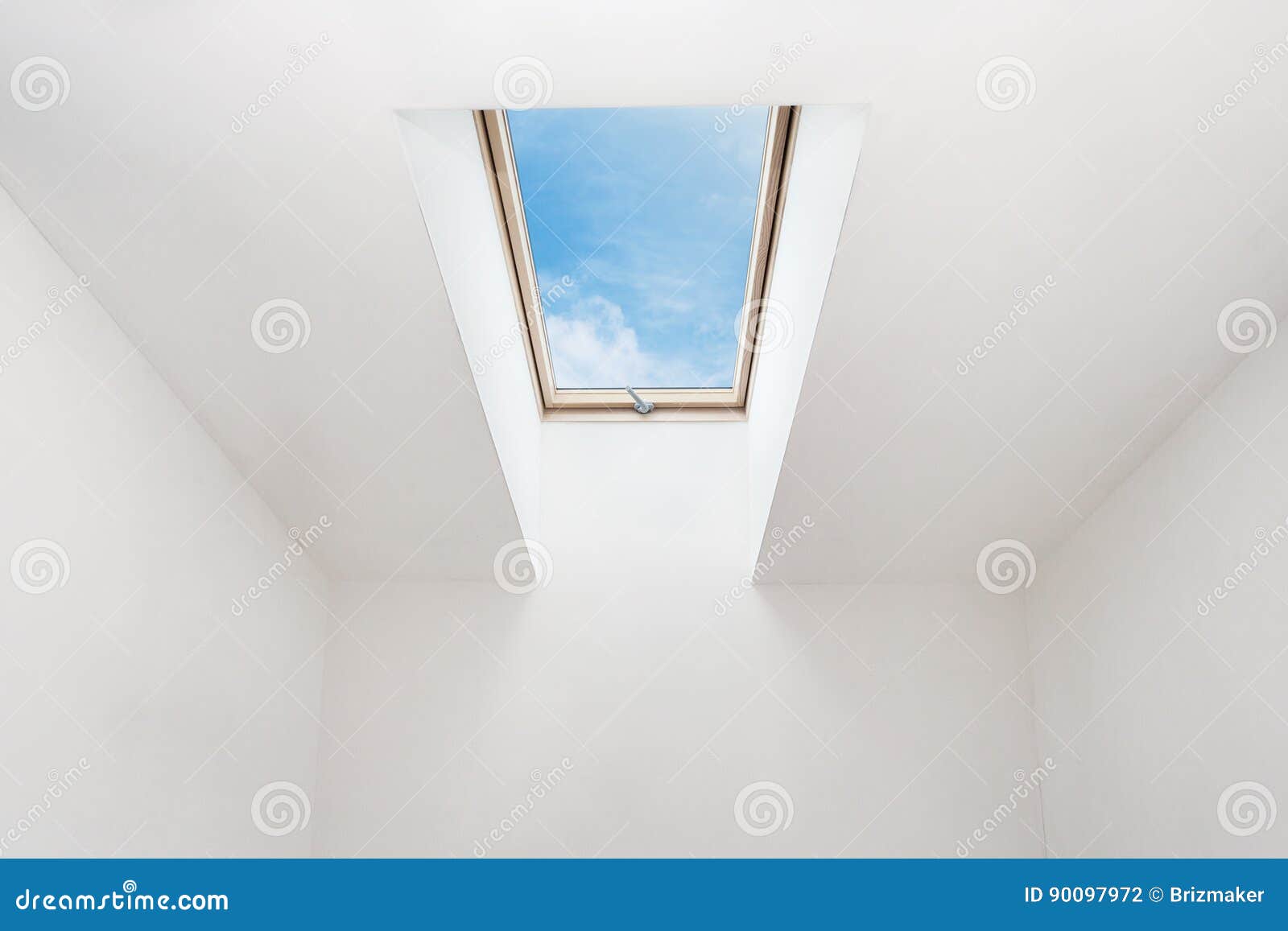 a modern open skylight mansard window in an attic room against blue sky.