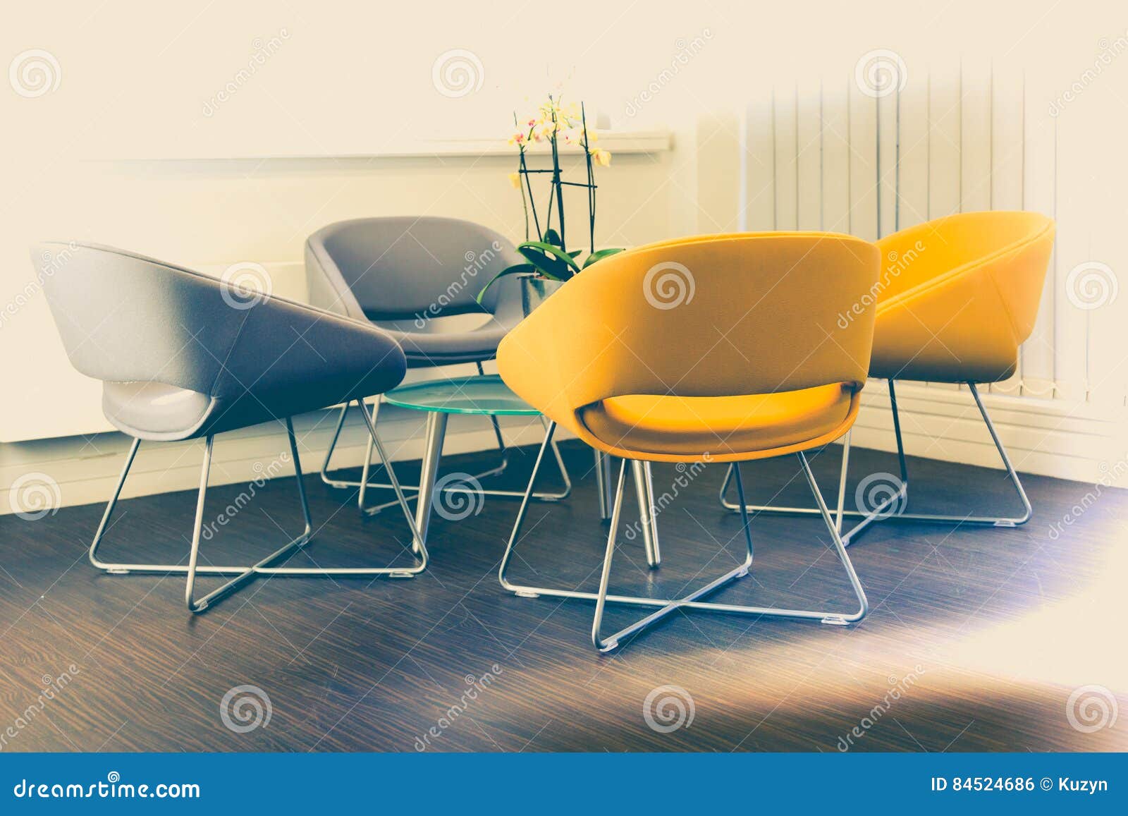 Modern yellow and grey armchairs in reception area in corporation office. Faded saturated tones with bright light spots