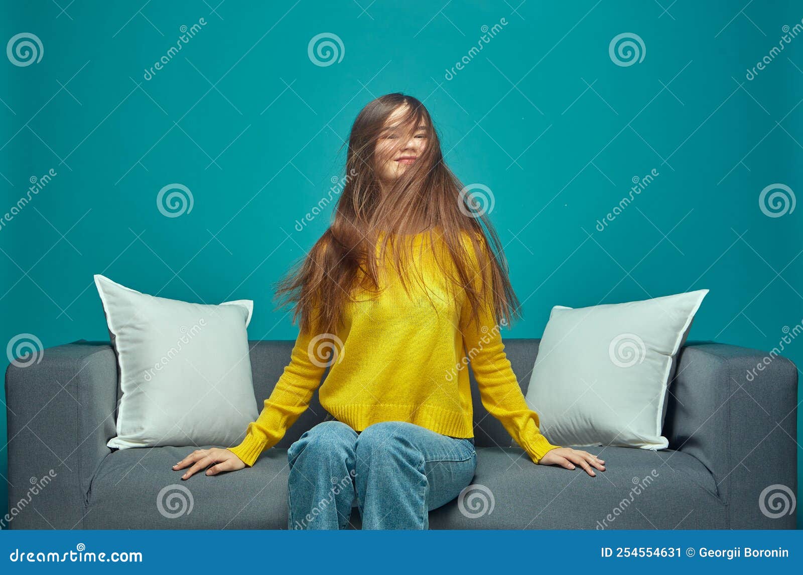Modern Young Girl Shaking Her Long Brown Tousled Hair Enjoying Haircare Result Sitting On Sofa