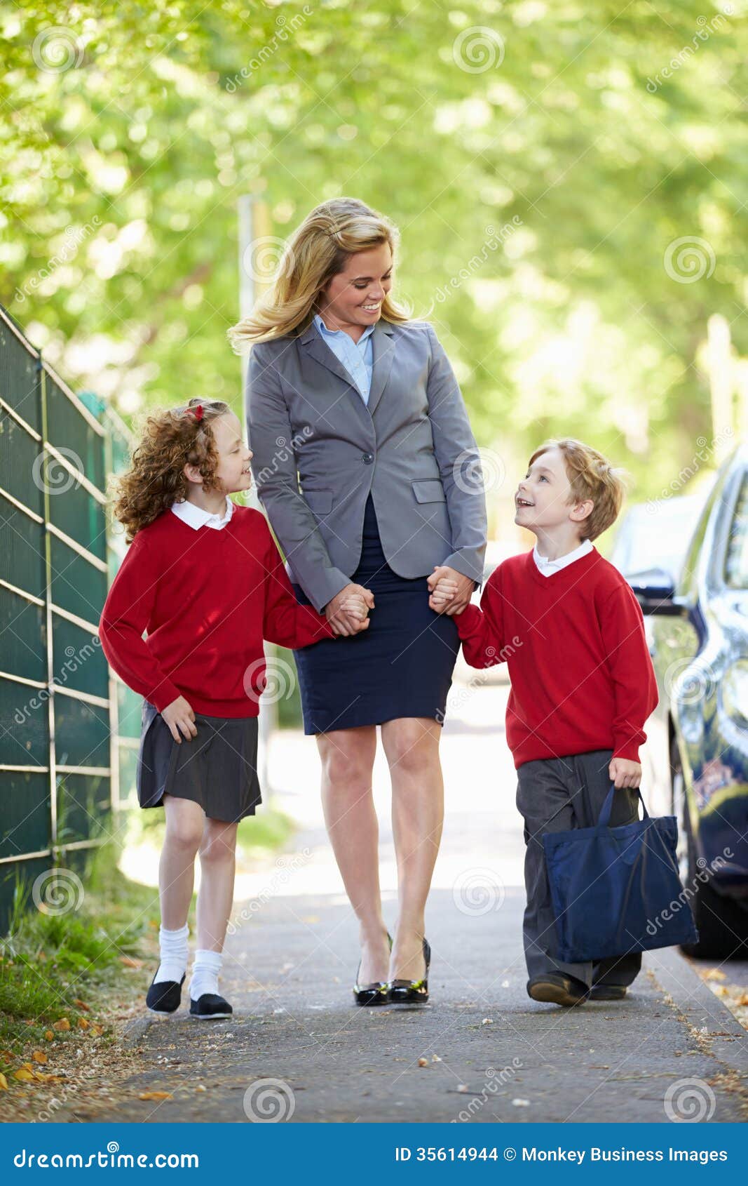 Moeder die aan School met Kinderen op Manier lopen te werken. Moeder die aan School met Kinderen op Manier lopen om het Glimlachen bij elkaar te werken terwijl Holdingshanden