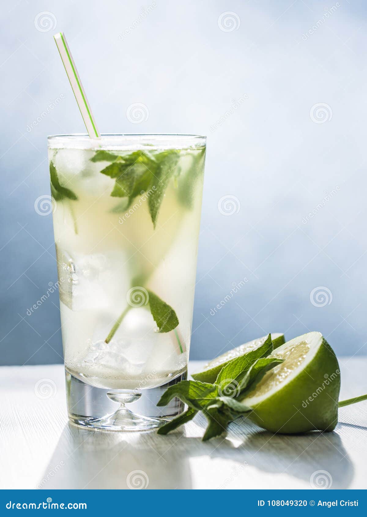mojito cocktail with lime, sugar, ice and mint leaves in the gray background.