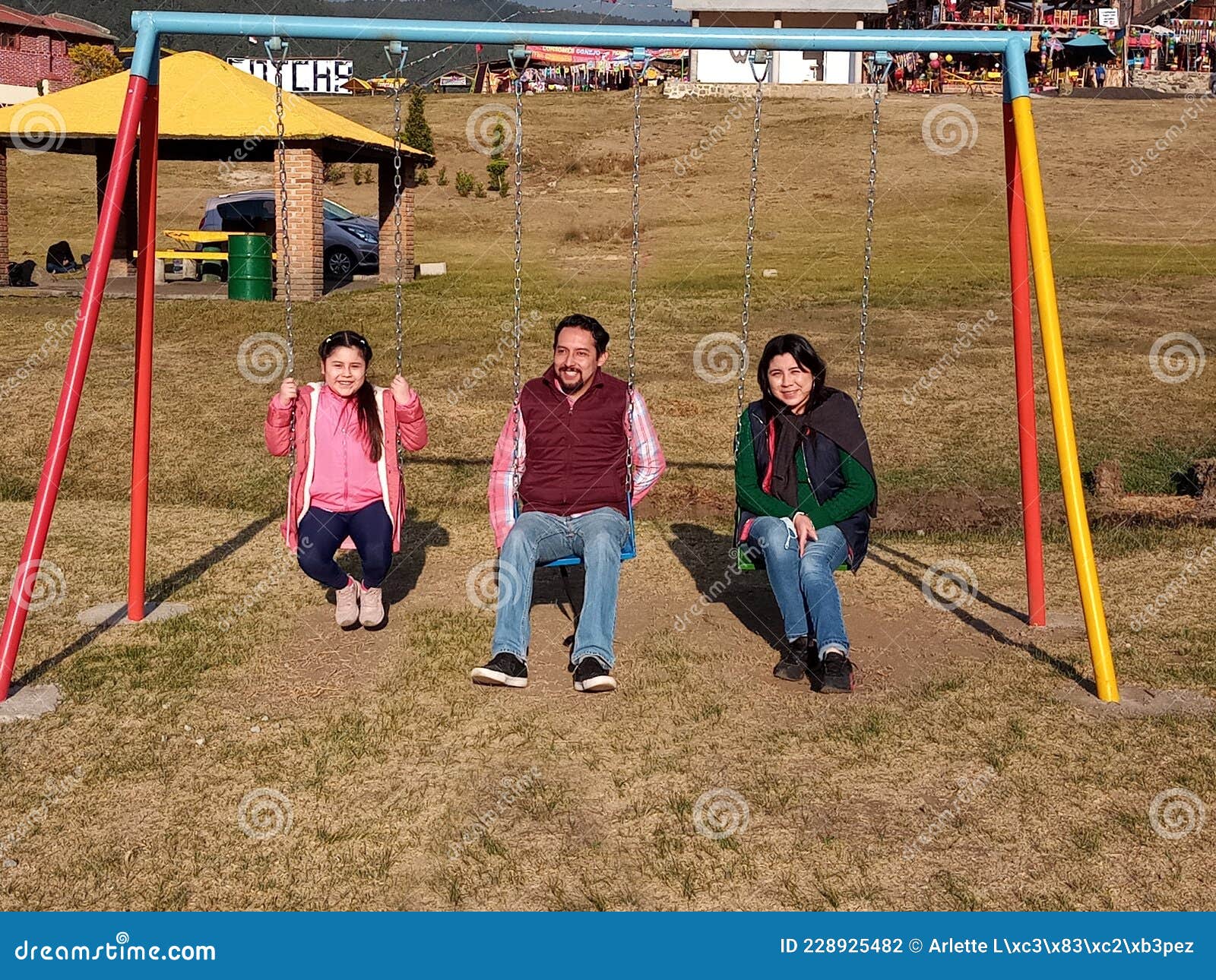 Mom, Dad and Daughter Playing on the Swings in the Middle of the Cold