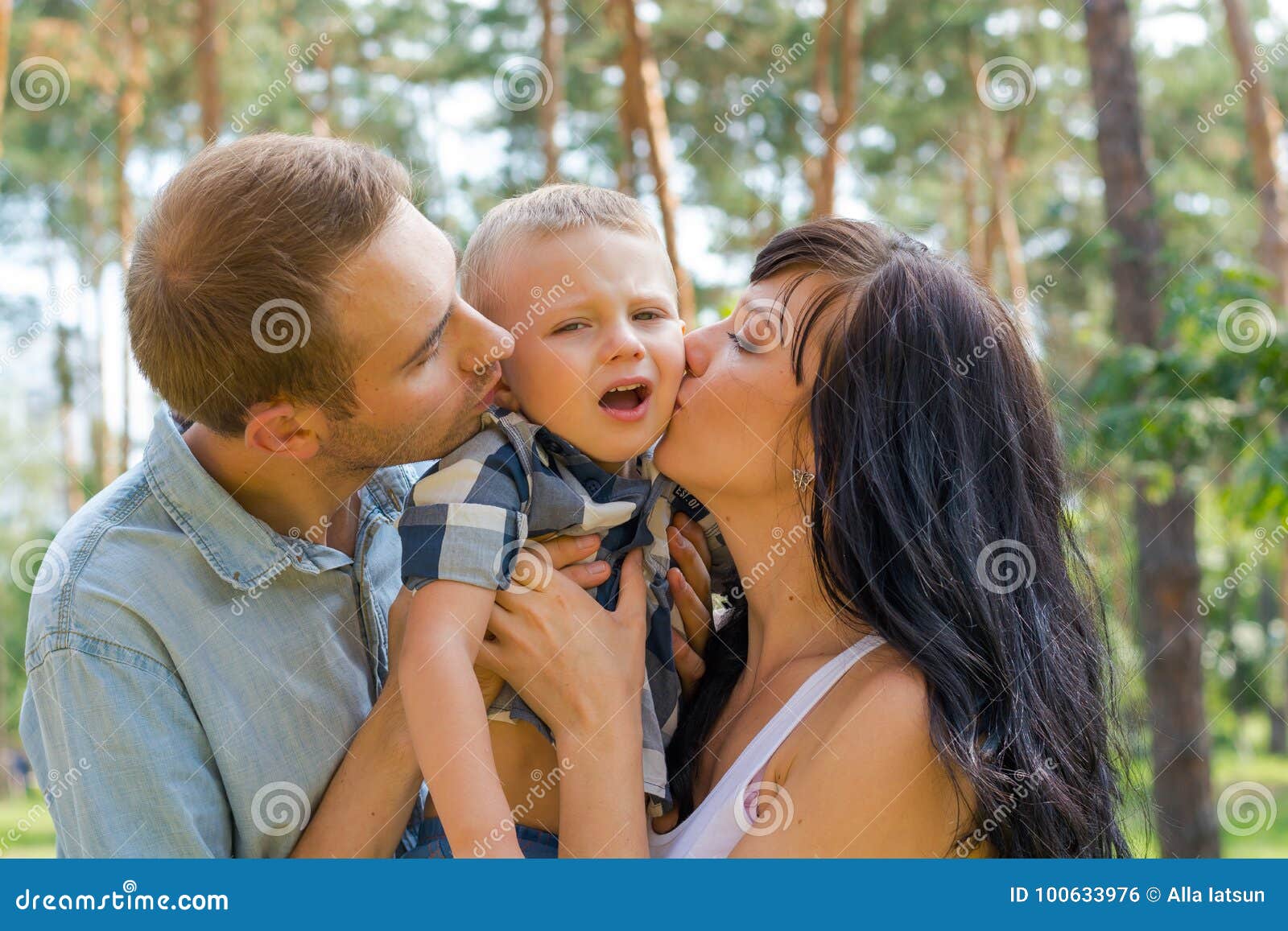 Mom and Dad Hug and Kiss Their Baby, and he`s Naughty. Stock Photo ...