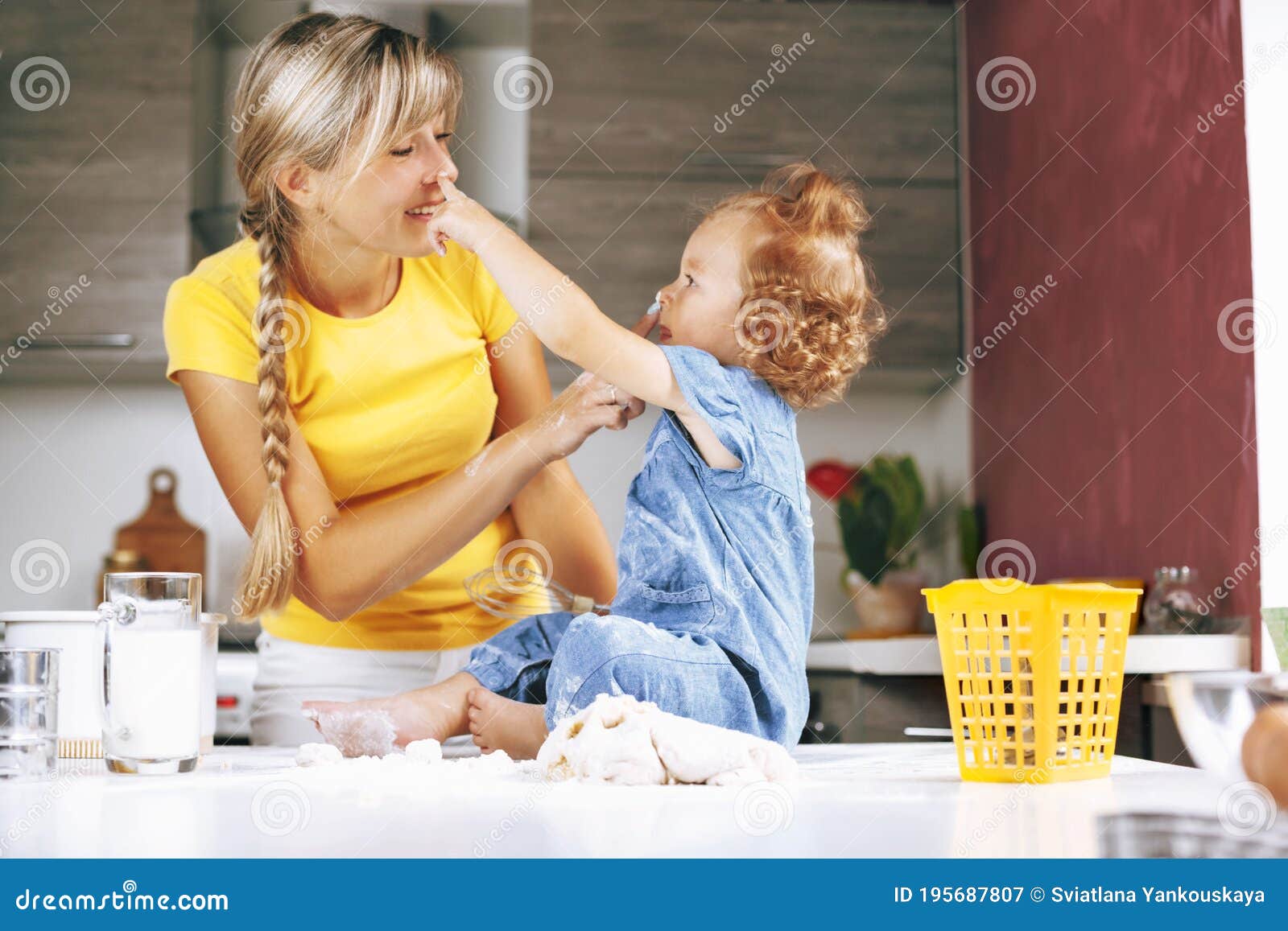 Mom And Daughter Are Cooking In The Kitchen Smiling And Playing On The Table Is The Dough 