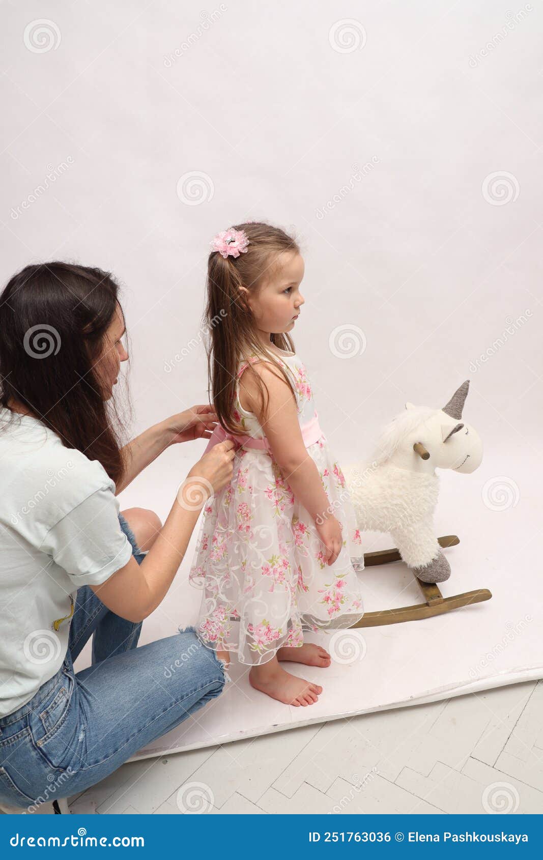 Mom Dresses Up Her Daughter. Mom Ties a Bow To Her Daughter. Preparing