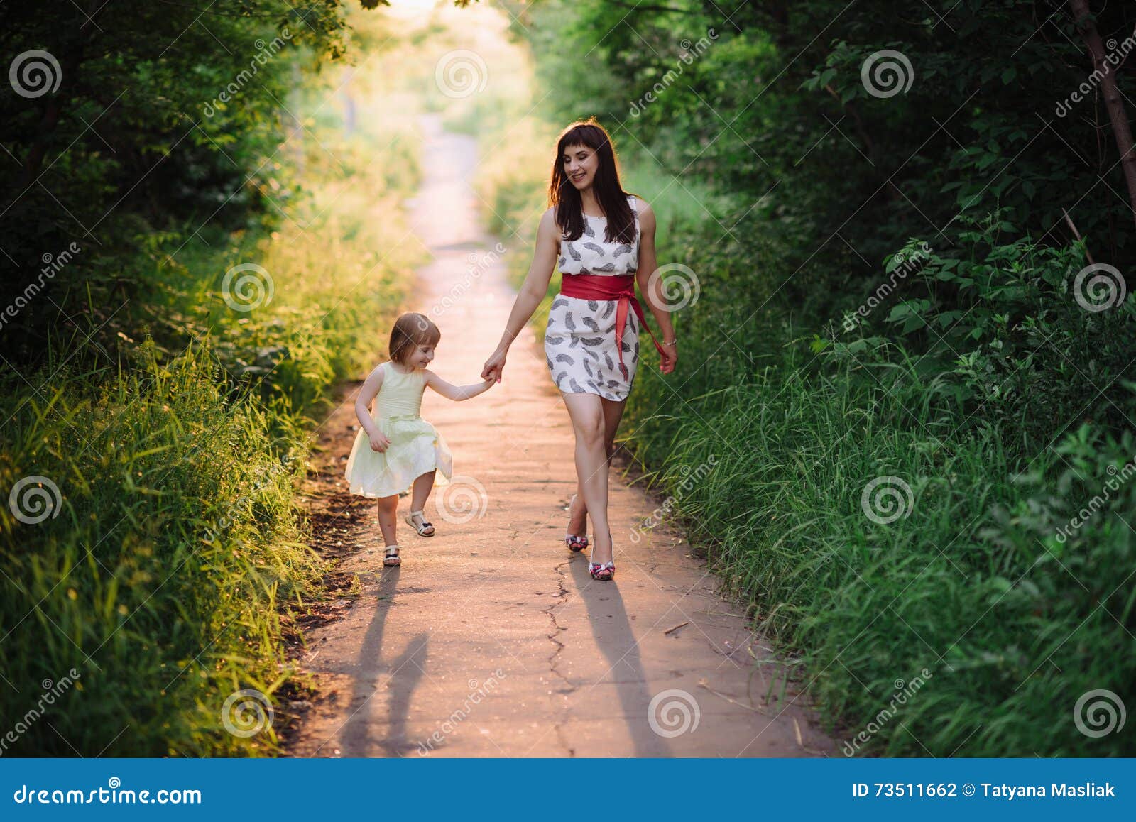 The Eldest Daughter Walks Down The Flower Path Mom Keeps Daughter S Hand and Walks the Walk on the Nature in Sunset