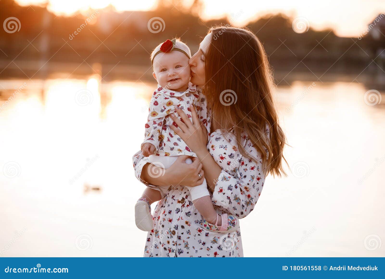 Girl kissing mother at a lake Stock Photo, Royalty Free 