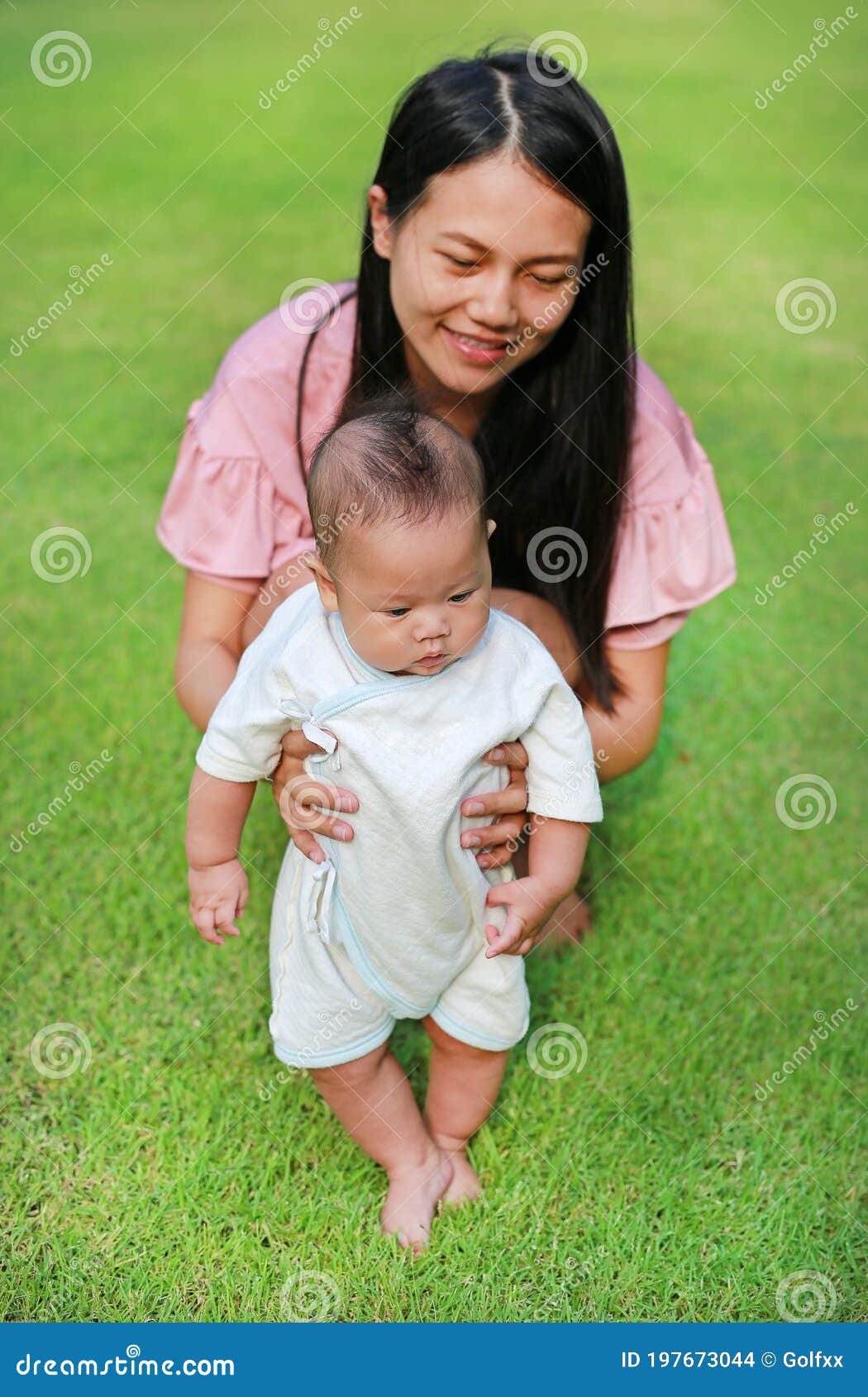 mom practiced her baby boy first step walking on green grass garden
