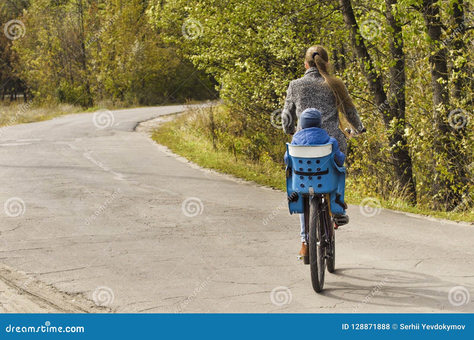 Mom And Son Are Riding A Bicycle On The Autumn Road Back View Stock