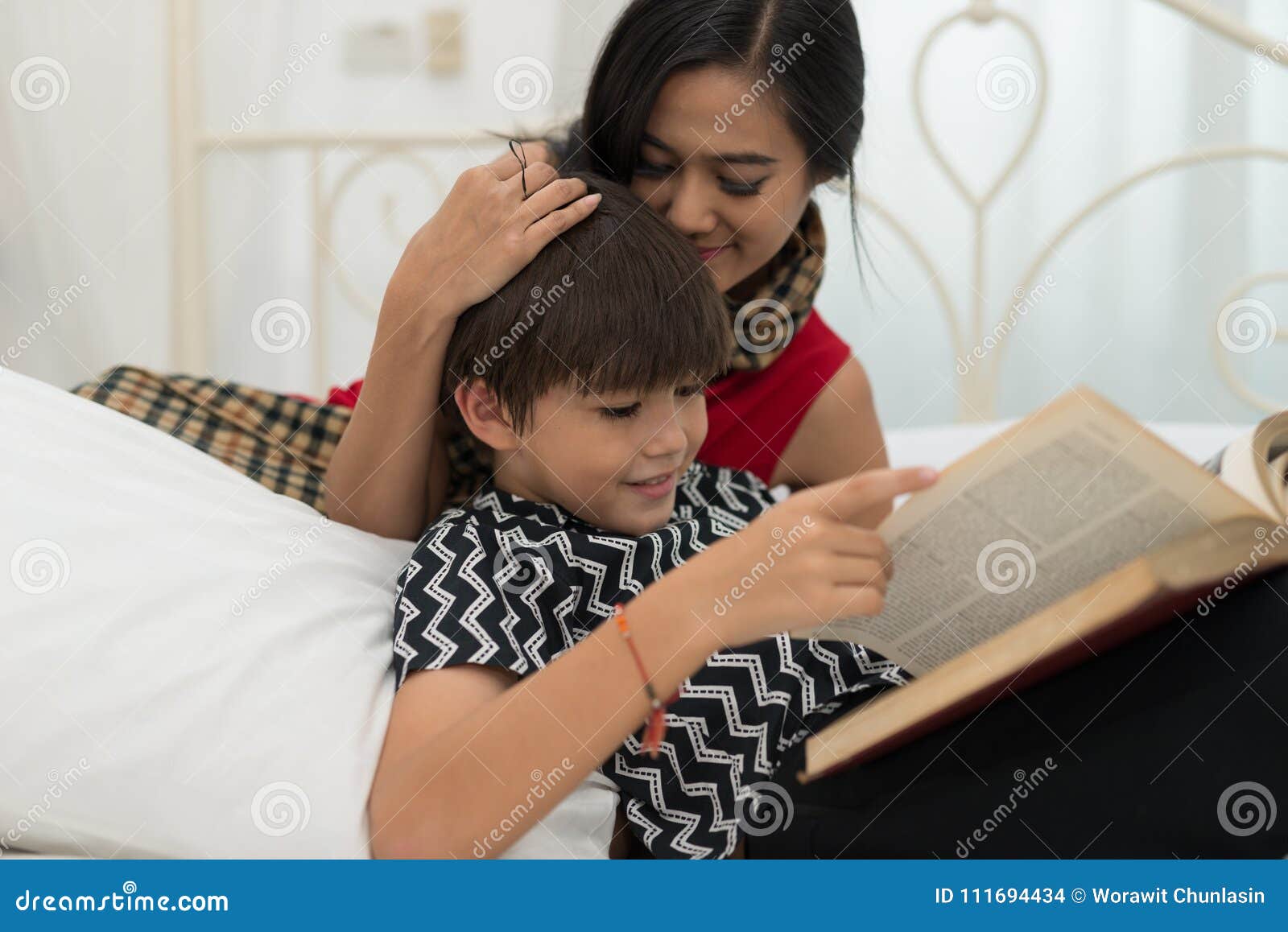 Mom Teach Son Reading a Book is on the Bed at H photo Mom Teach Son Reading a Book is on the Bed at H image