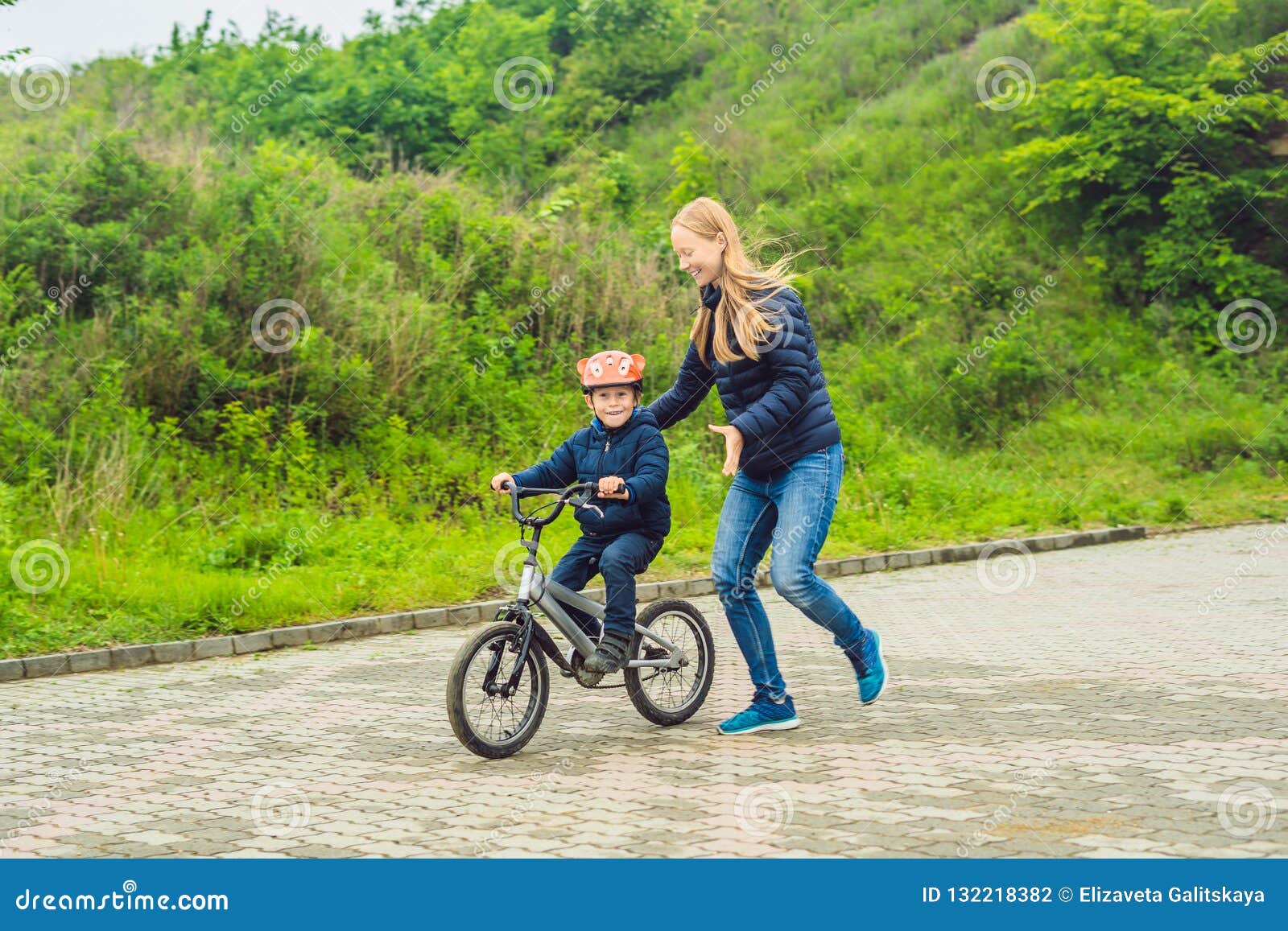 Mom Teaches Son To Ride a Bike in the Park Stock Photo