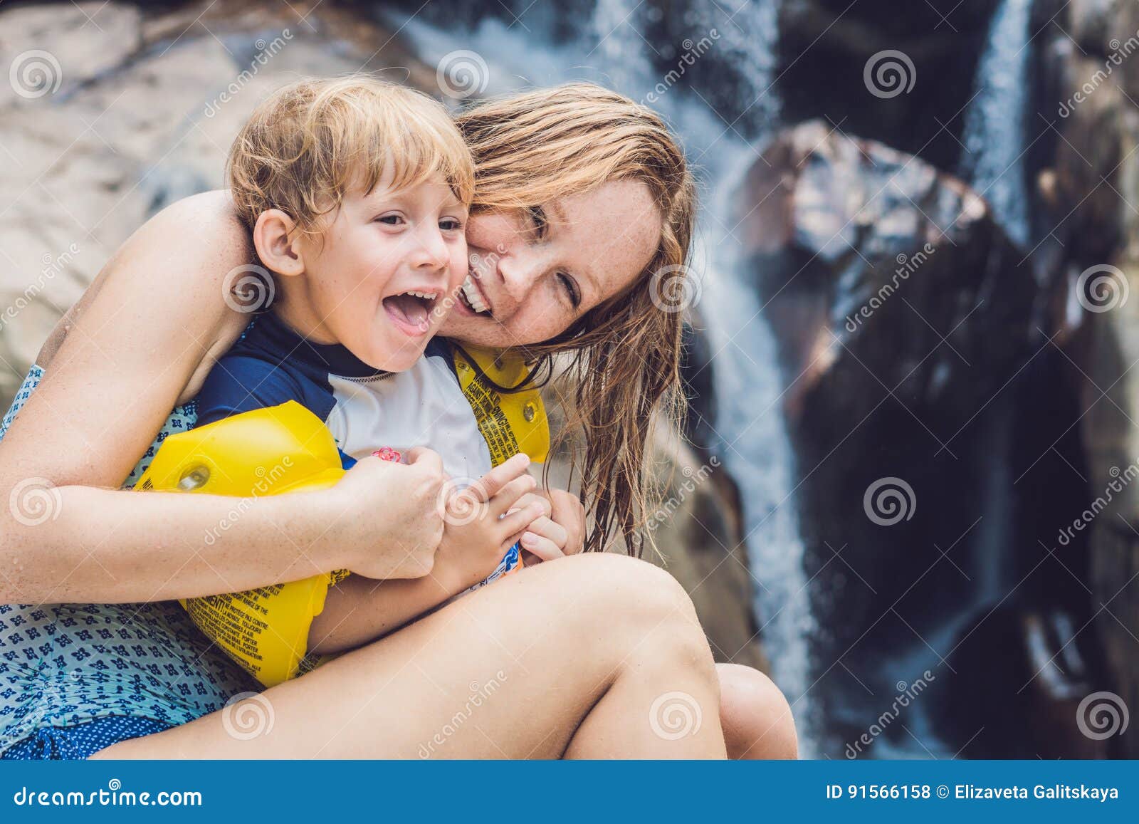 Mom And Young Son On The Waterfall Backgro photo