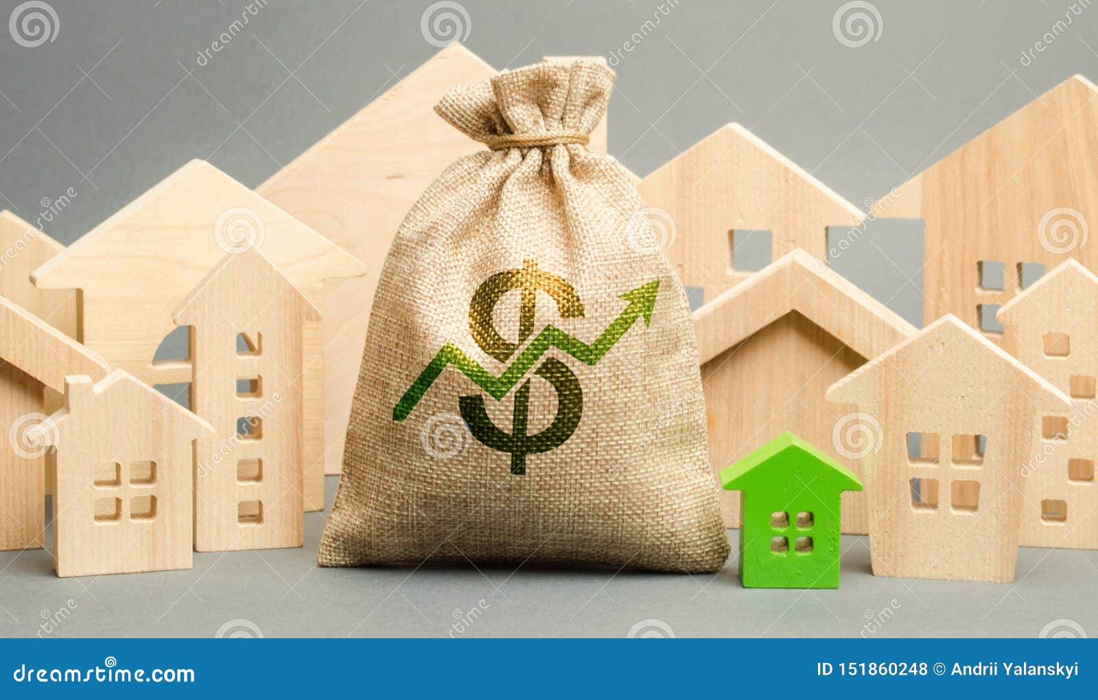 money bag with arrow up and miniature wooden houses. the concept of rising property prices. high mortgage rates. expensive rental