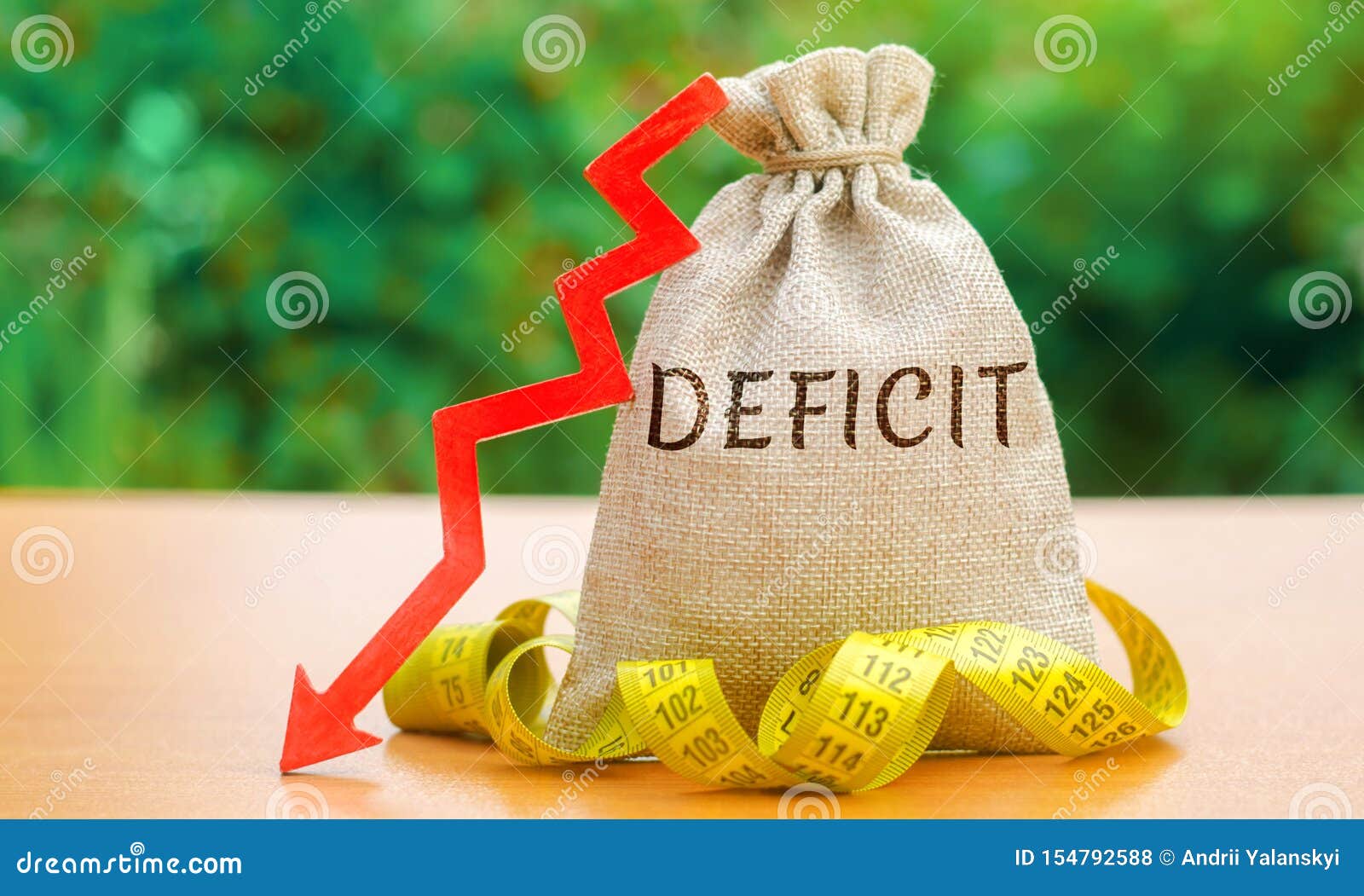 money bag with the word deficit and tape measure with down arrow. budget deficit concept. low profit. financial costs. bankruptcy